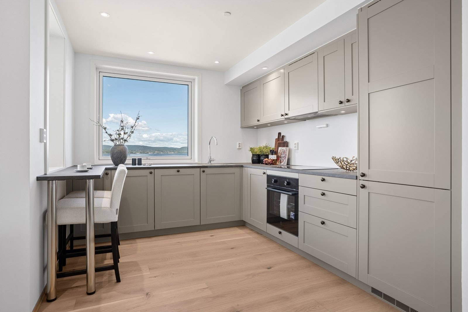 Her er den en stilfull kjøkkeninnredning utført med glatte fronter og laminat benkeplate. Innredningen tilbyr godt med lagringsløsninger gjennom mange skap og skuffer, og er utstyrt med moderne, integrerte hvitevarer. Galleribilde