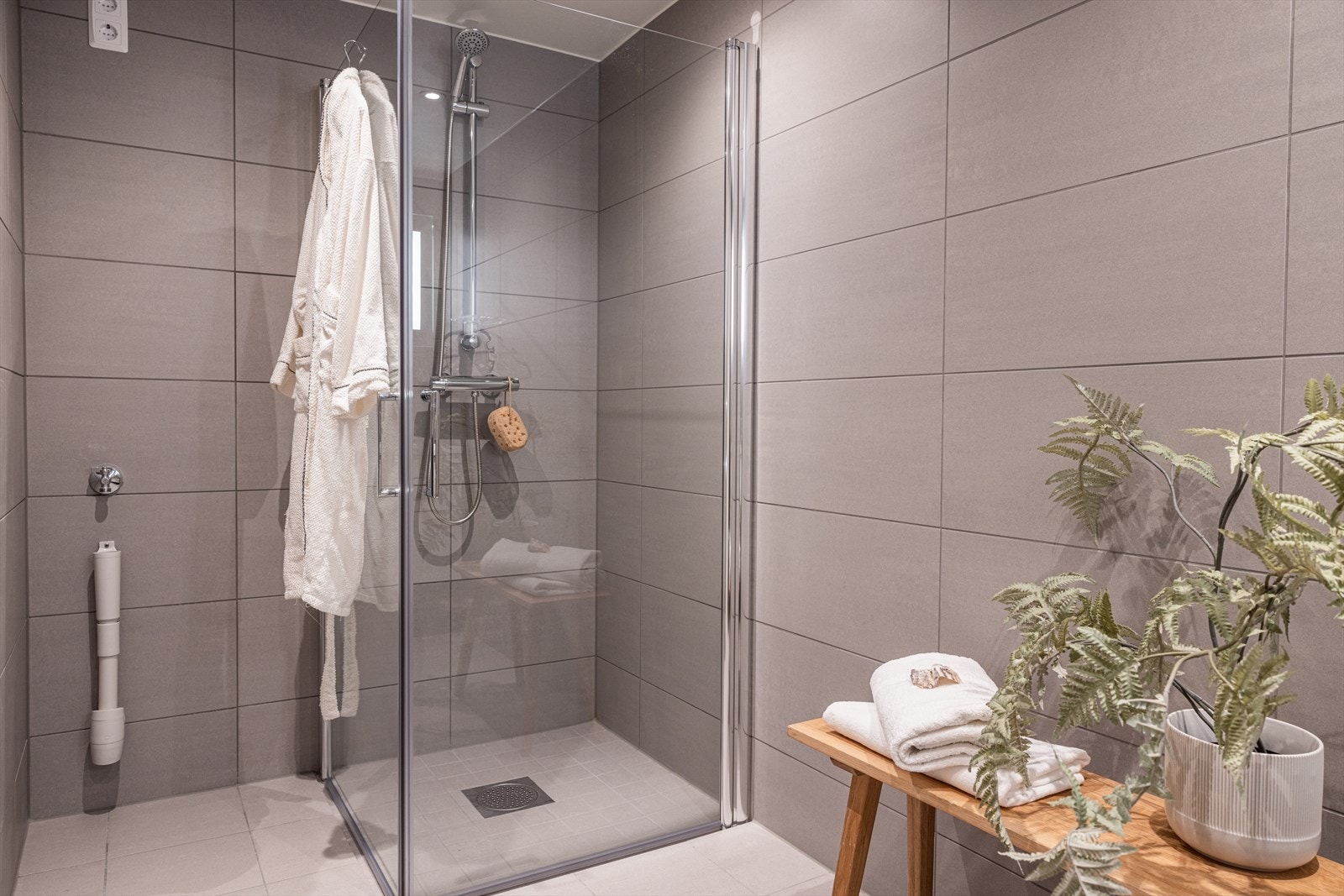 Rommet er innredet med vegghengt toalett, dusjhjørne med glassdører samt servant med underskuffer. Galleribilde