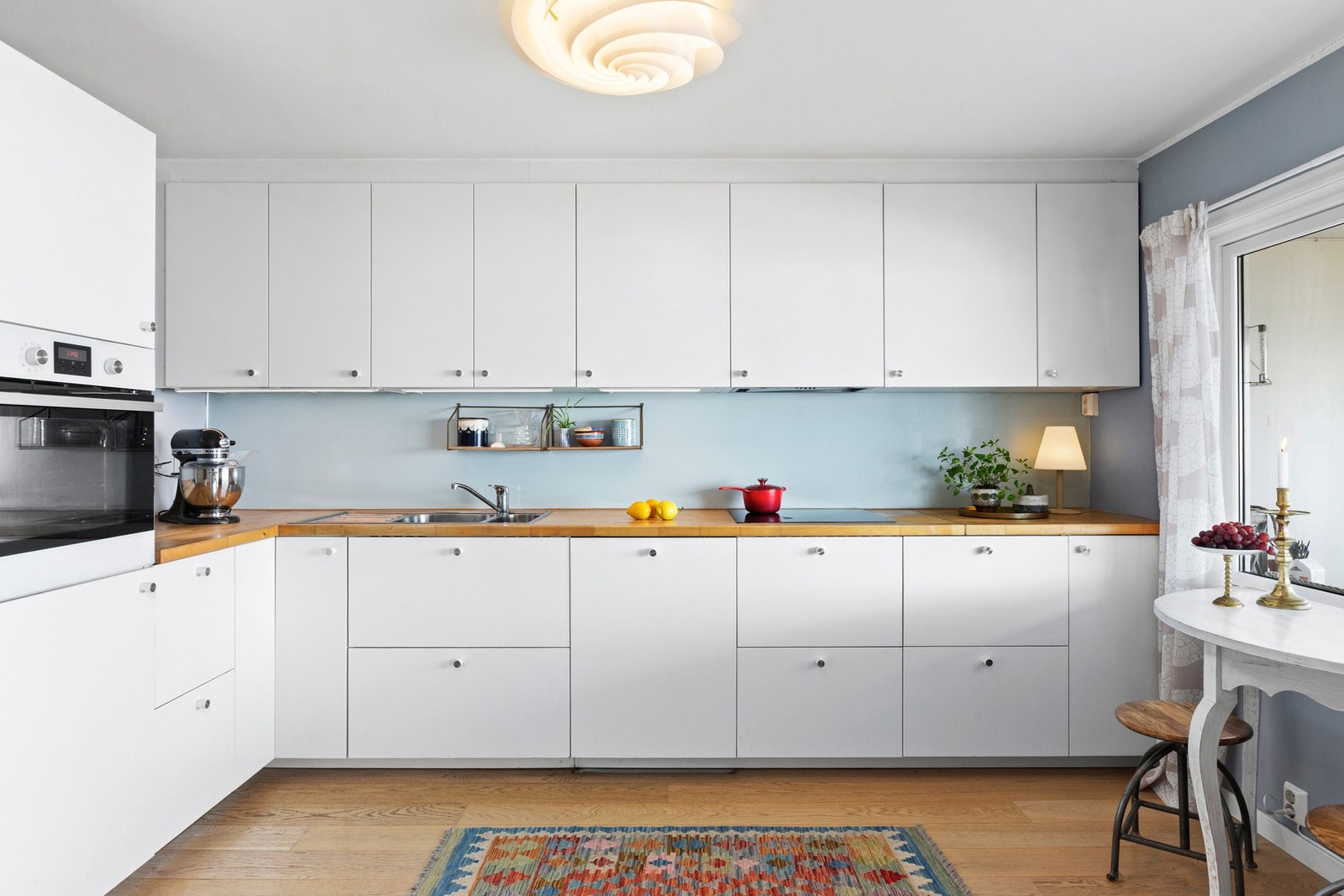 Moderne kjøkken med integrerte hvitevarer, lyse skap og en benkeplate i tre. Galleribilde