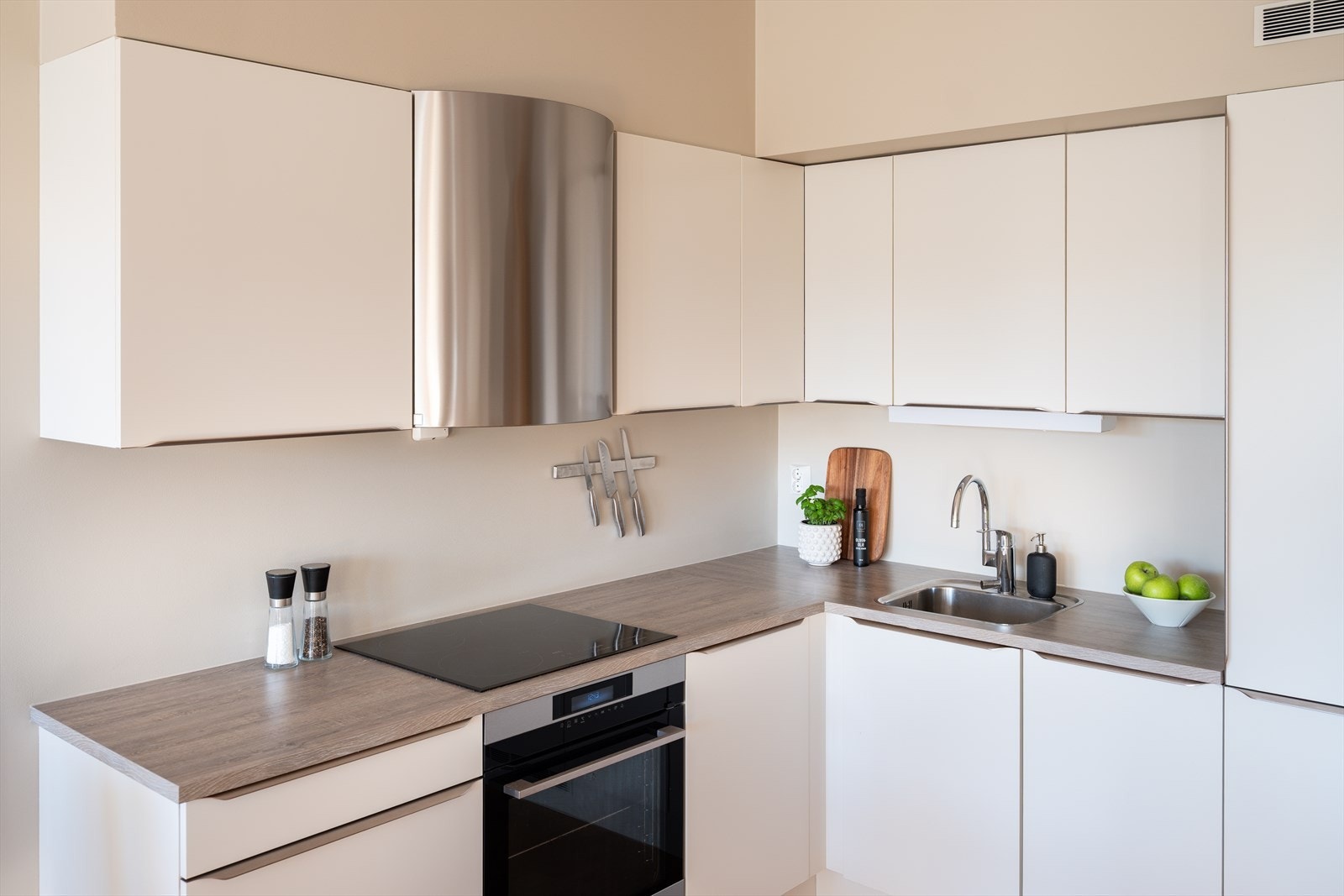 Kjøkkenet har integrerte hvitevarer som platetopp, stekeovn, oppvaskmaskin og kombinert kjøl og fryseskap. Galleribilde