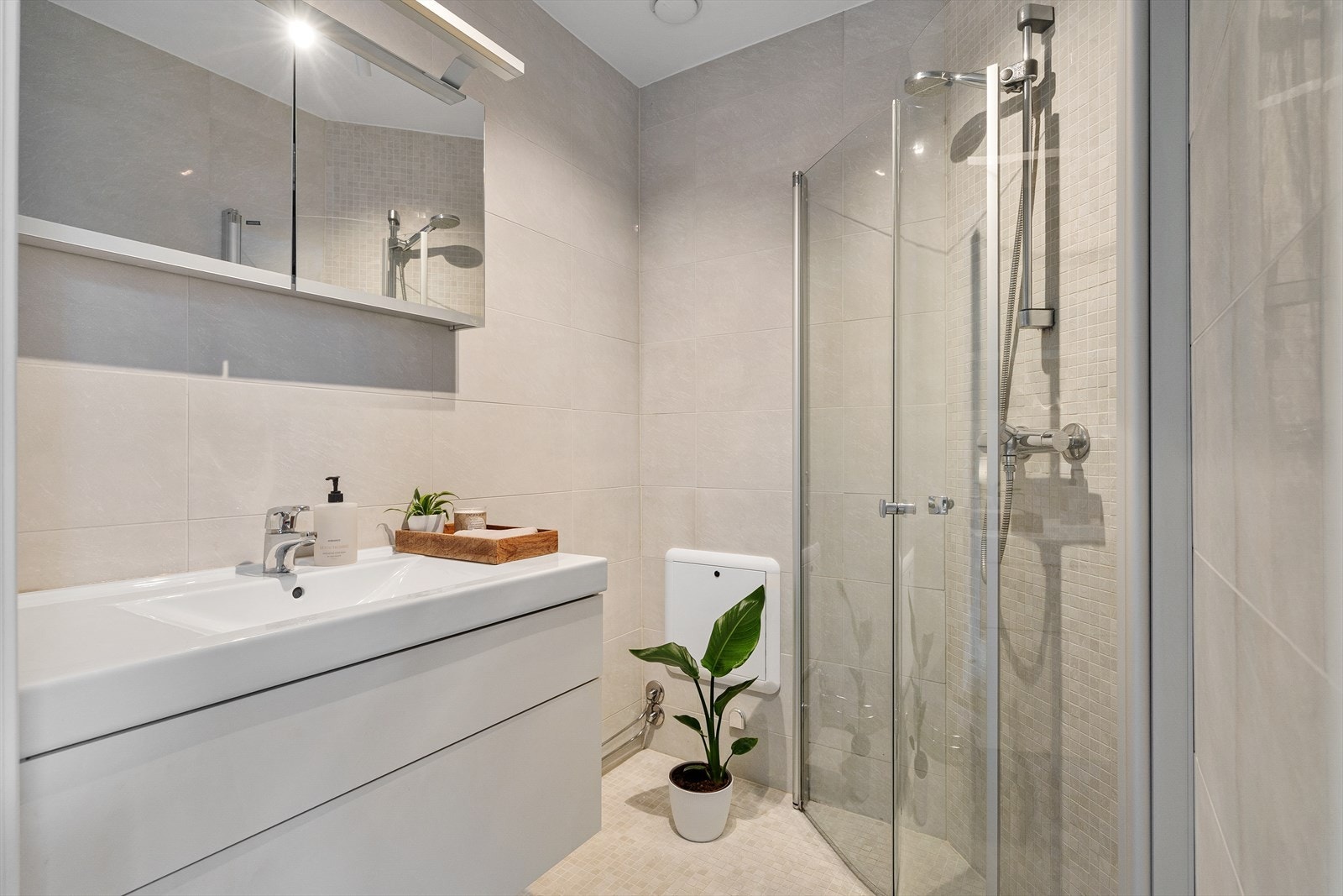 Badet er innredet med nedfelt servant i baderomsinnredning og separat dusjhjørne med glassvegger. Galleribilde