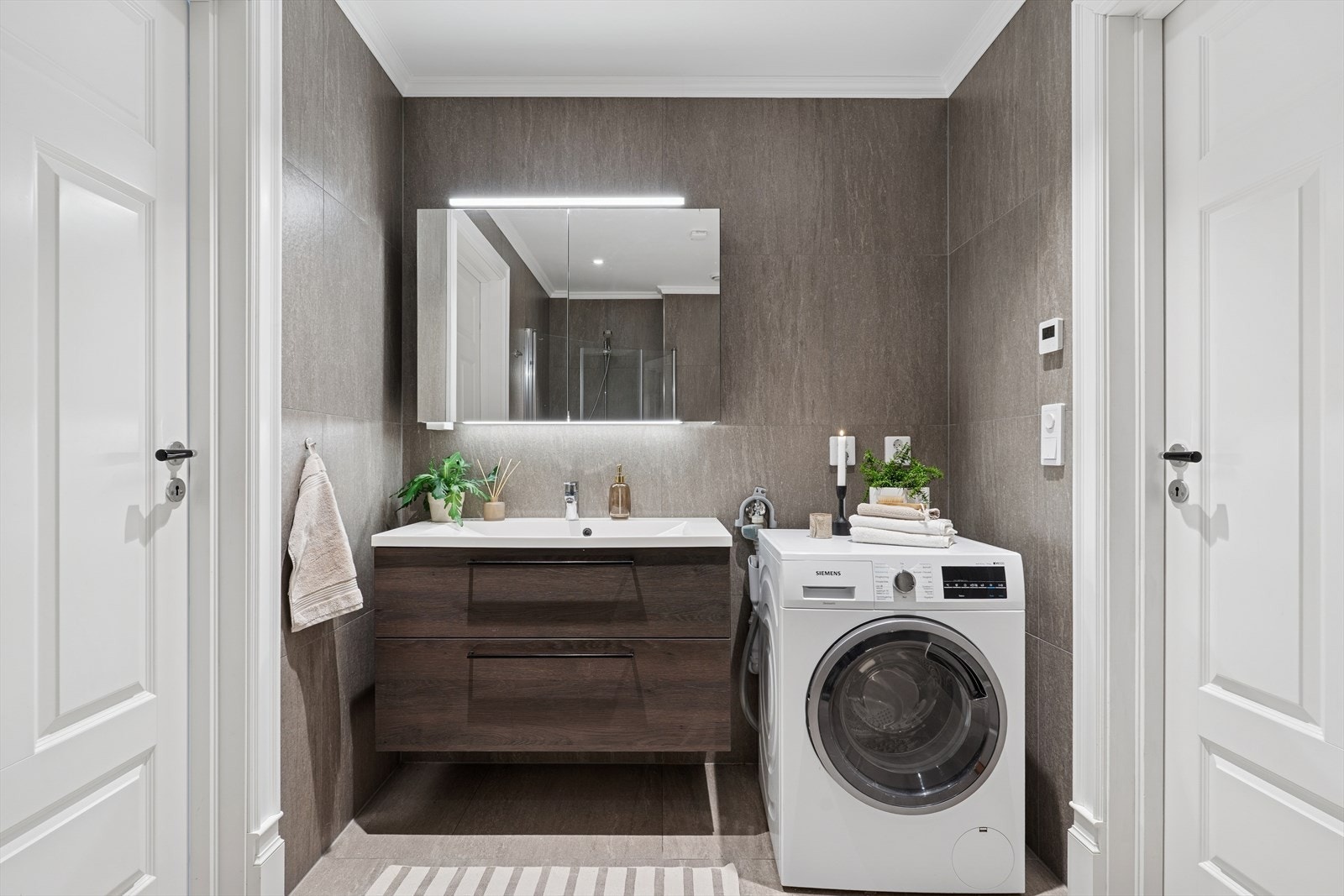 Stilfull og moderne baderomsinnredning med gode skuffer, servant og speilskap. Opplegg for vaskemaskin. Galleribilde