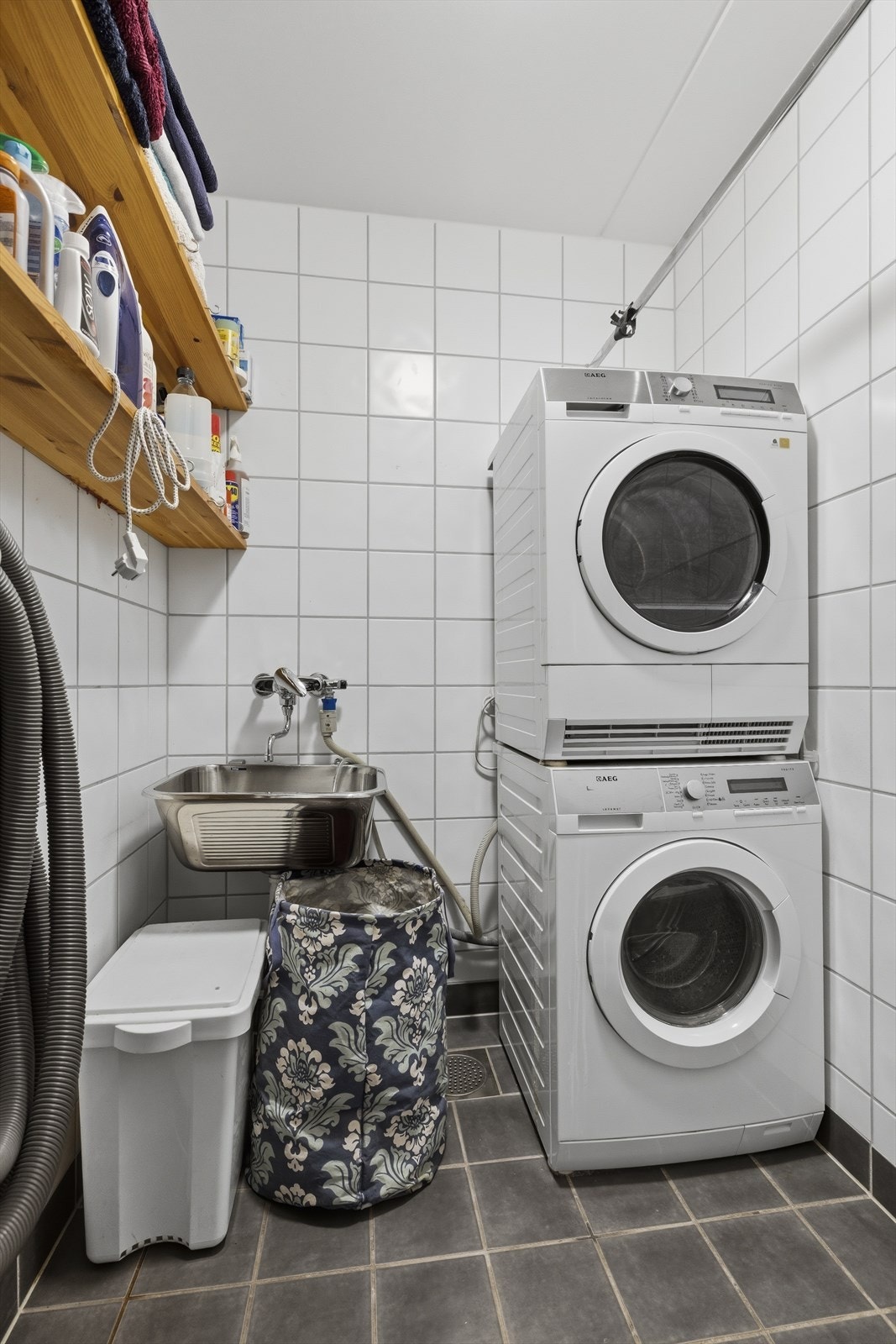 Praktisk separat vaskerom med flislagt gulv over varmekabler. Vaskerommet har utslagsvask i stål og opplegg til vaskesøyle Galleribilde