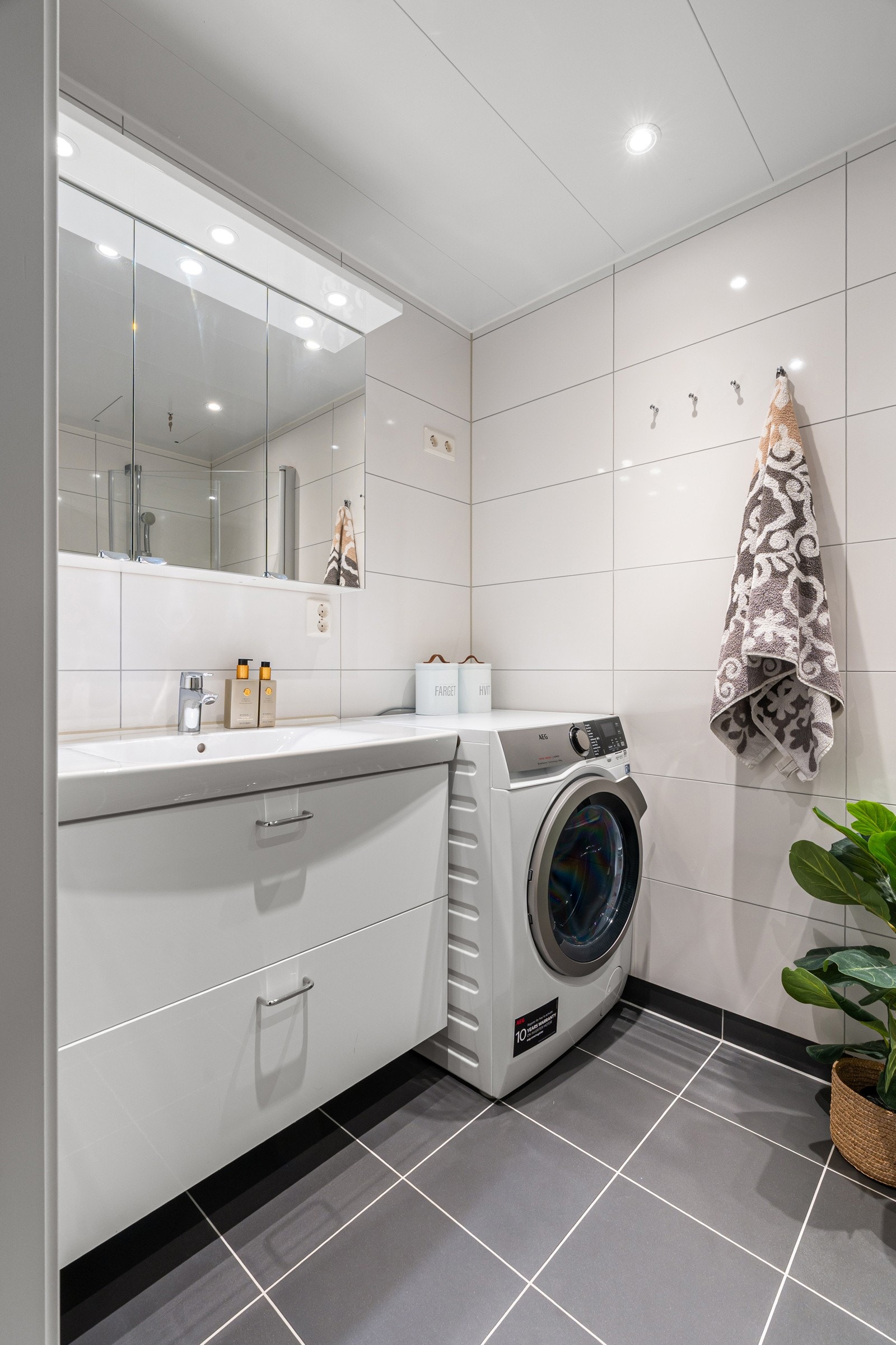 Moderne innredning med overspeilskap med belysning og plass til vaskemaskin/tørketrommel.