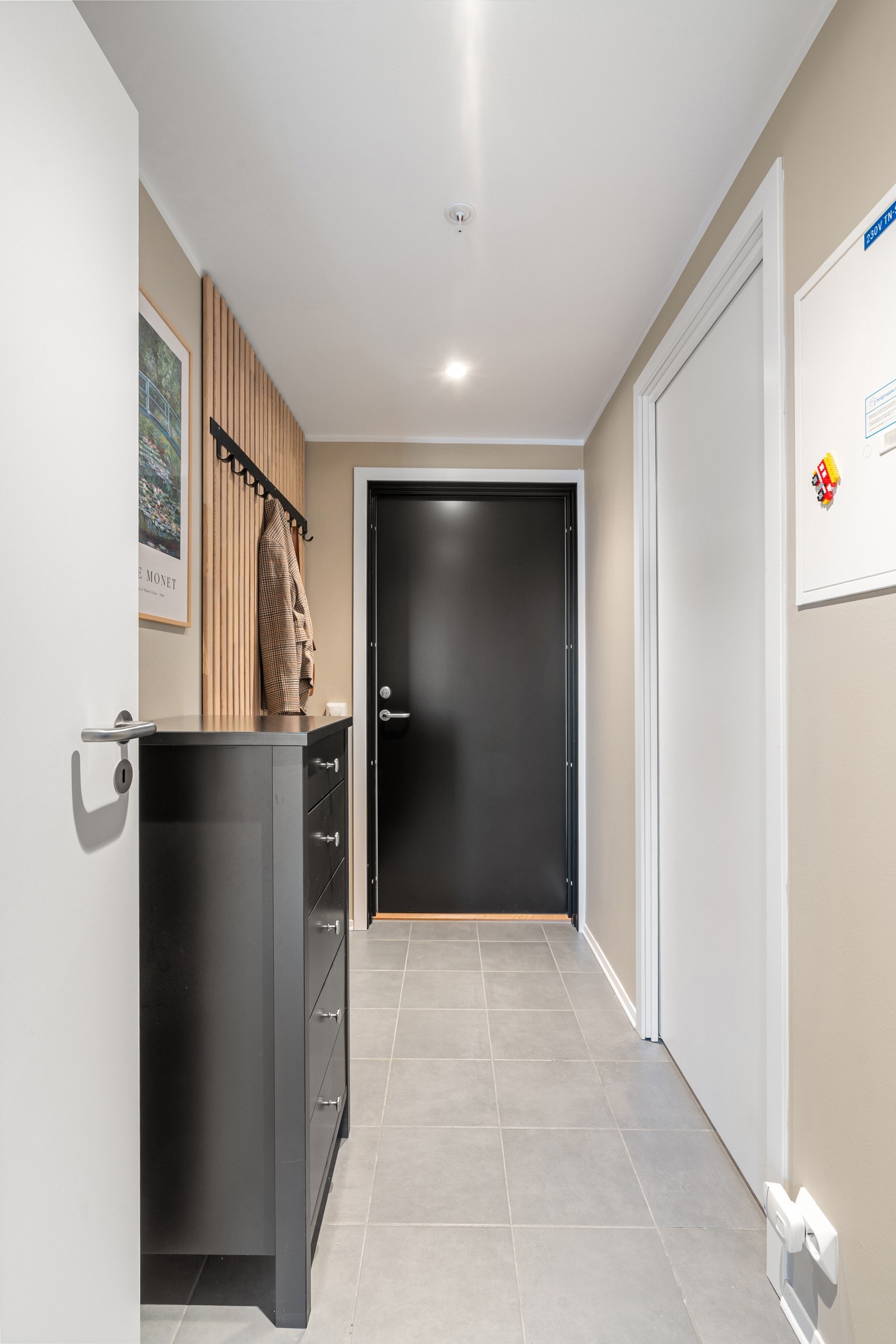 Flislagt gang med praktiske oppbevaringsløsninger for yttertøyet.