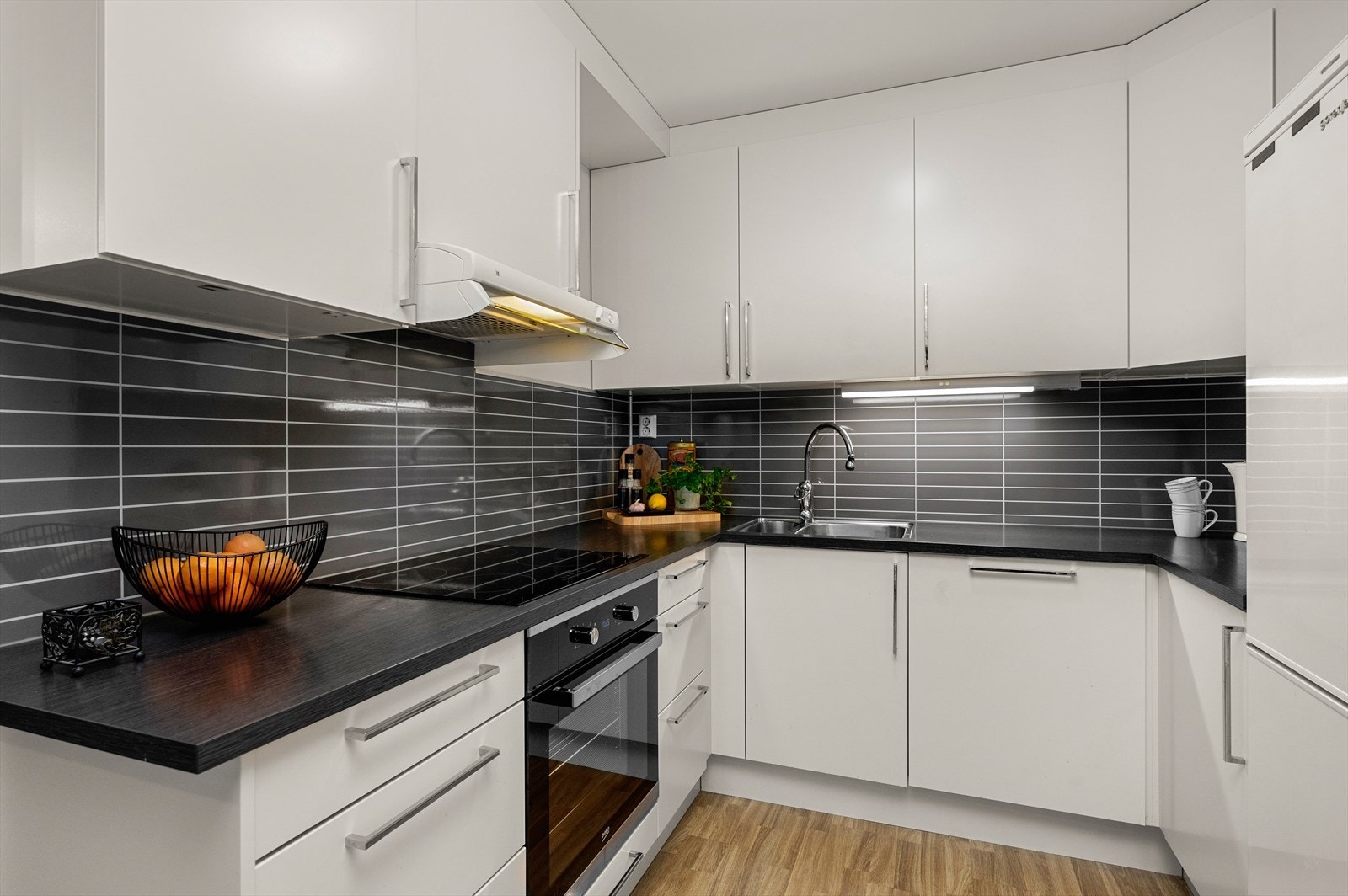 Det er også praktisk 1+1/2 utslagsvask som er nedfelt i benkeplate, soft close på skuffer og skap og fliseminerte plater over steke og vannsone for enklere rengjøring Galleribilde