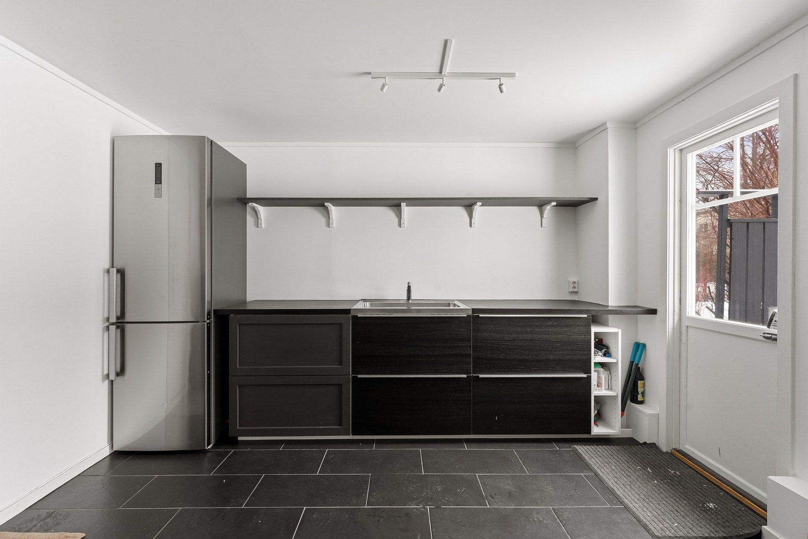 Praktisk uterom i tilknytting til den store uteplassen. Innredet med en enkel kjøkkenbenk, lagringsplass og kjøleskap. Galleribilde