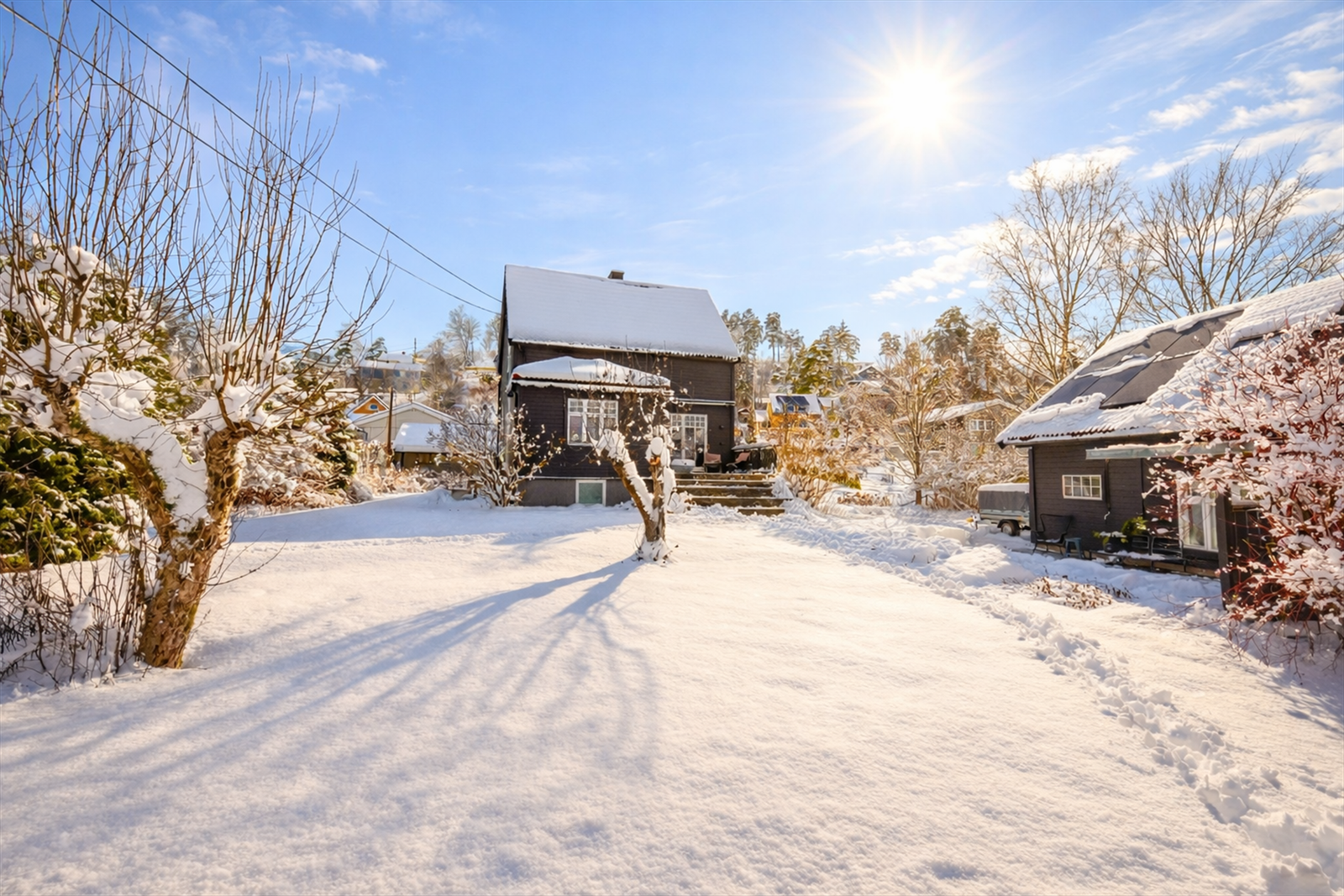 Eiendommen er pent opparbeidet med plen, busker og trær. Galleribilde