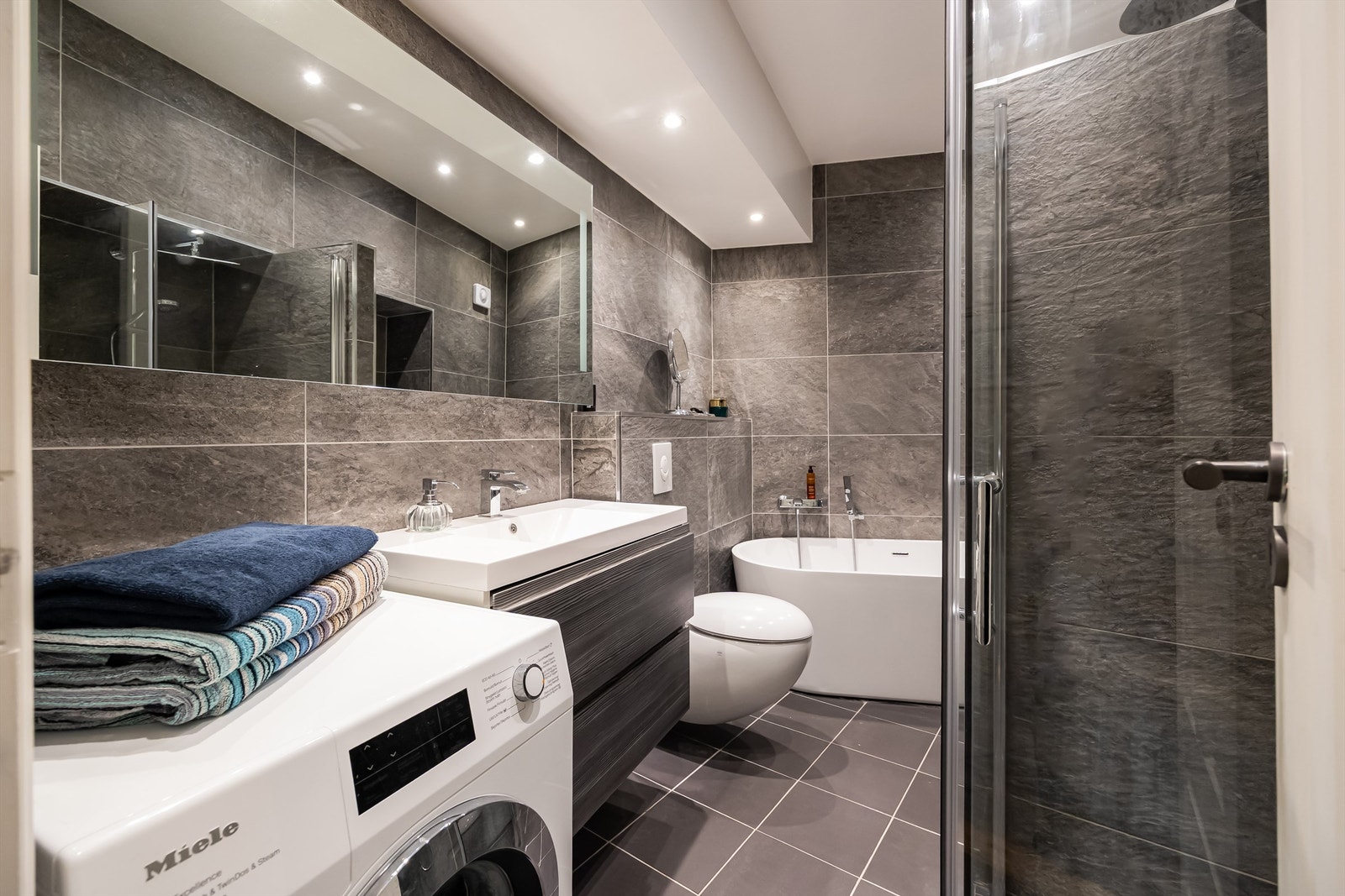 Leiligheten har et moderne og stilrent bad fra 2014, med store fliser på gulv og vegger, gulvvarme og downlights i himlingen. Galleribilde