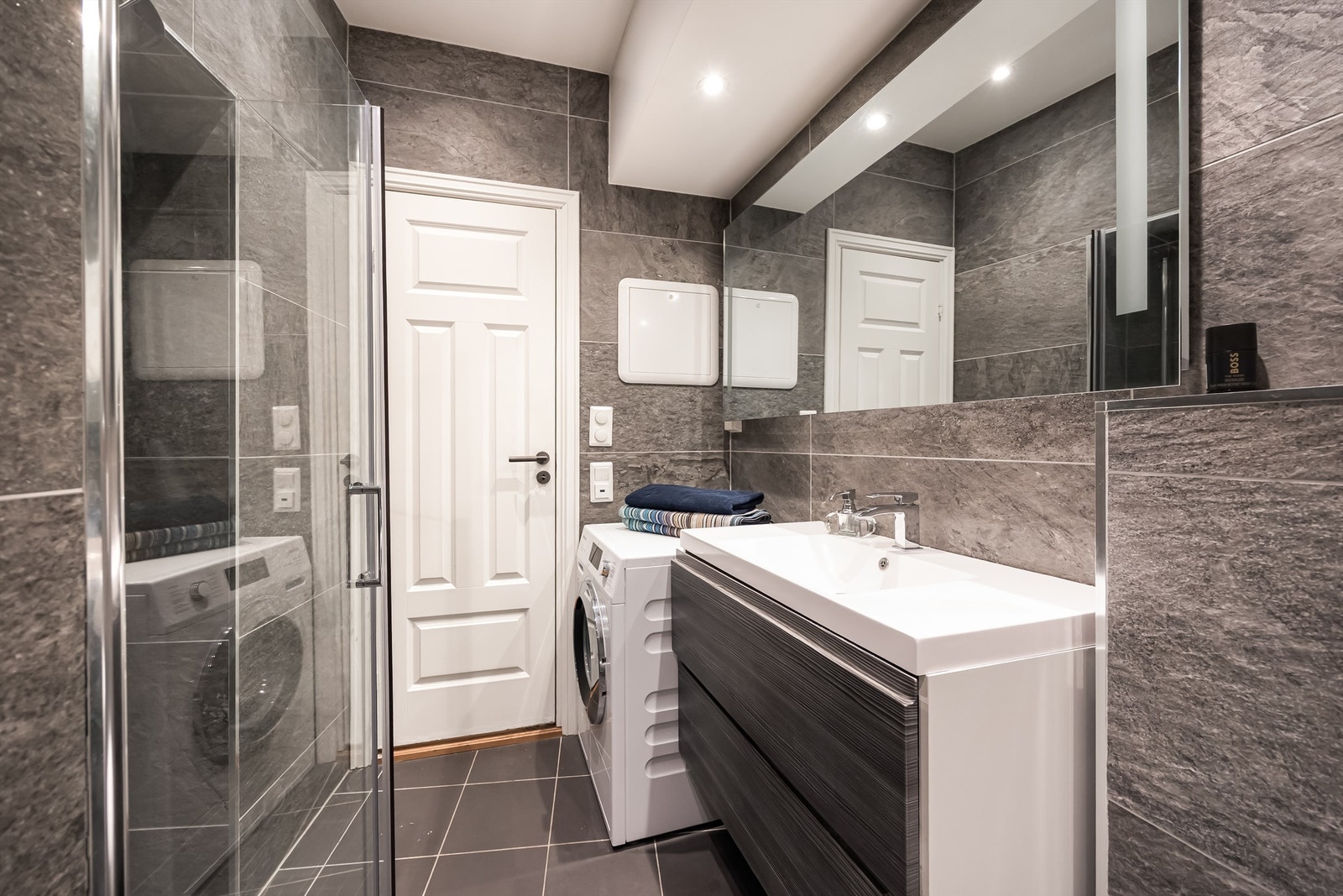 Innredningen består av vegghengt servantskap med god oppbevaring, speil med belysning og vegghengt toalett. Det er også opplegg for vaskemaskin. Galleribilde