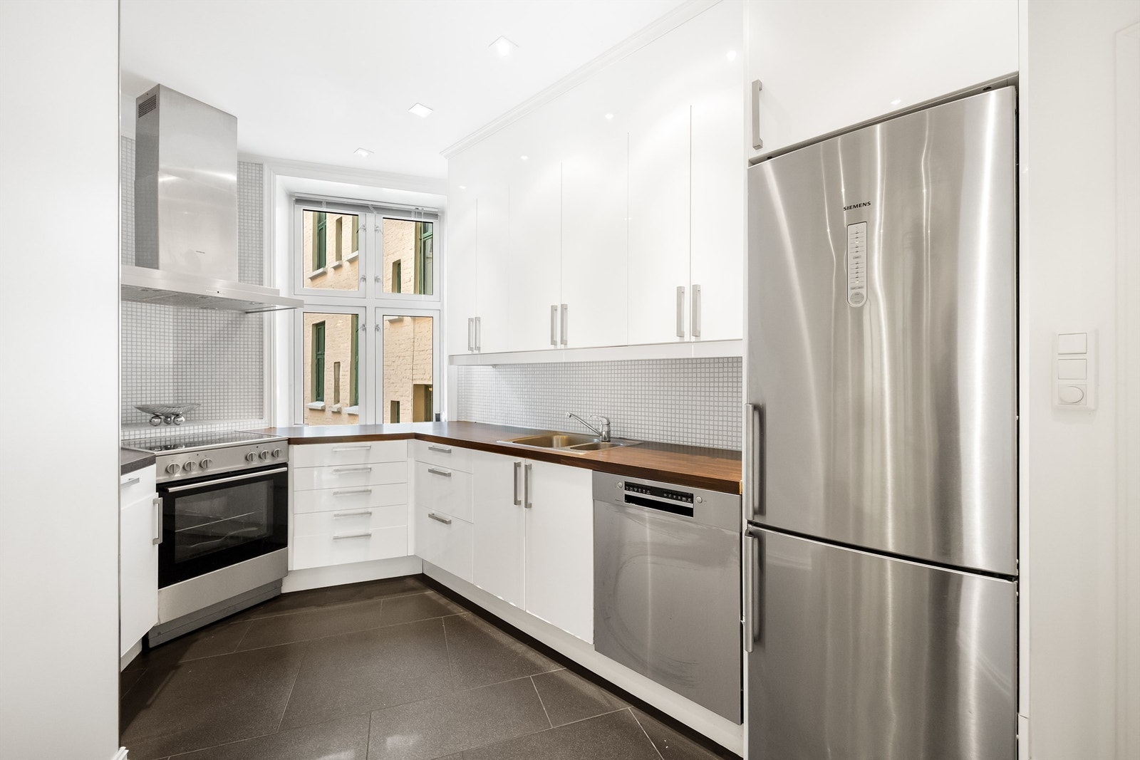 Leiligheten har et lyst og funksjonelt kjøkken med slette, hvite fronter og god skap- og benkeplass. Galleribilde