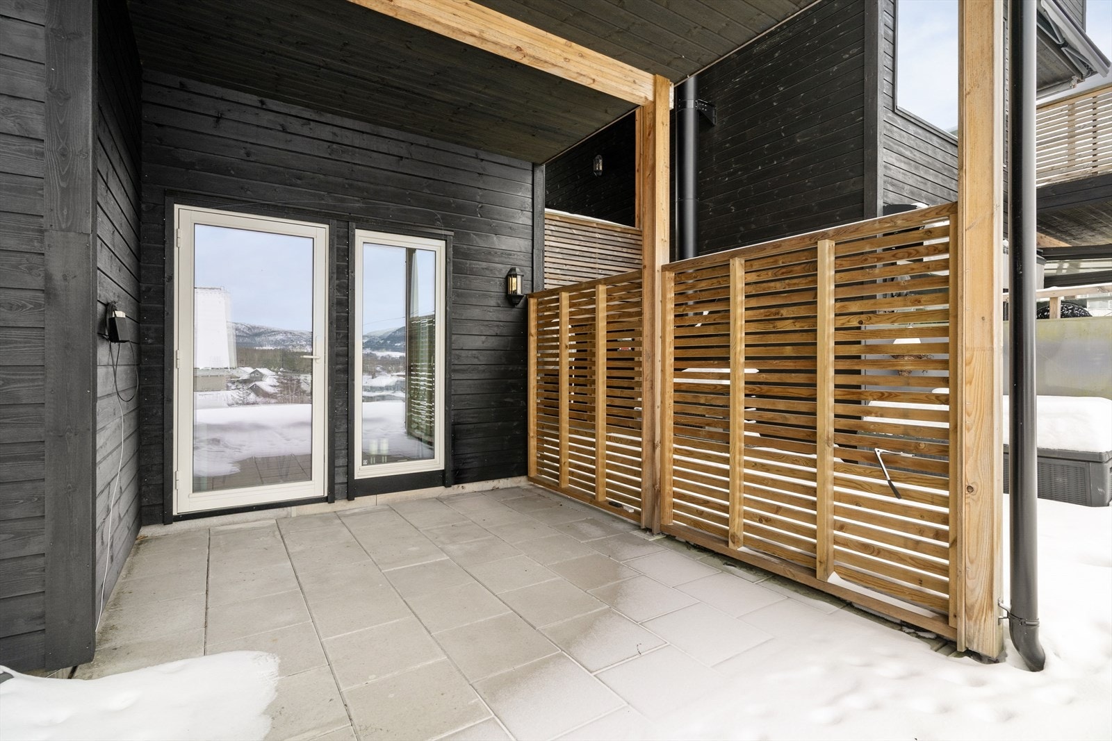 Den lune, solrike terrassen har høy og fin skillevegg med moderne spiler som skjermer for vær og vind. Galleribilde