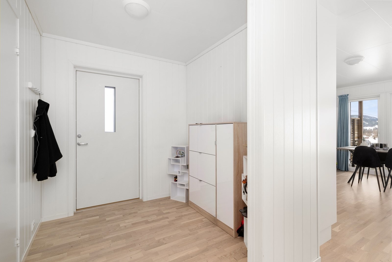 Med adkomst fra hyggelig, overbygget inngangsparti kommer man inn i boligens entrè hvor det er parkett på gulvet som går videre inn i leiligheten og gir en fin helhet. Her er det plass til oppbevaringsmøblement, eller mulighet for skyvedørsgarderobe. Galleribilde