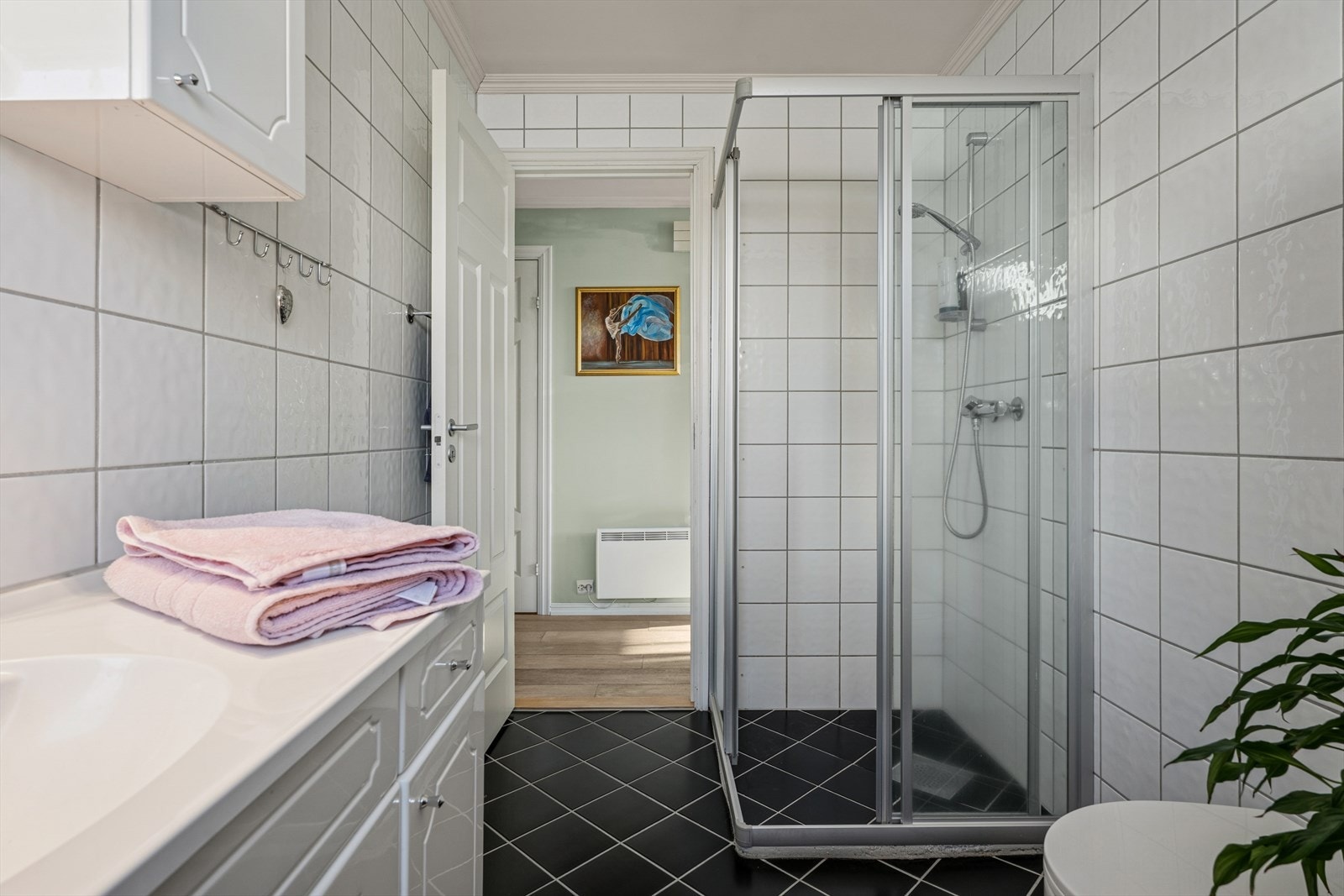 Rommet har baderomsinnredning med heldekkende servant og underskap med skuffer/dører, veggmontert toalett og dusjhjørne med dører i herdet glass. Det er også tappekran og avløp for vaskemaskin. Galleribilde