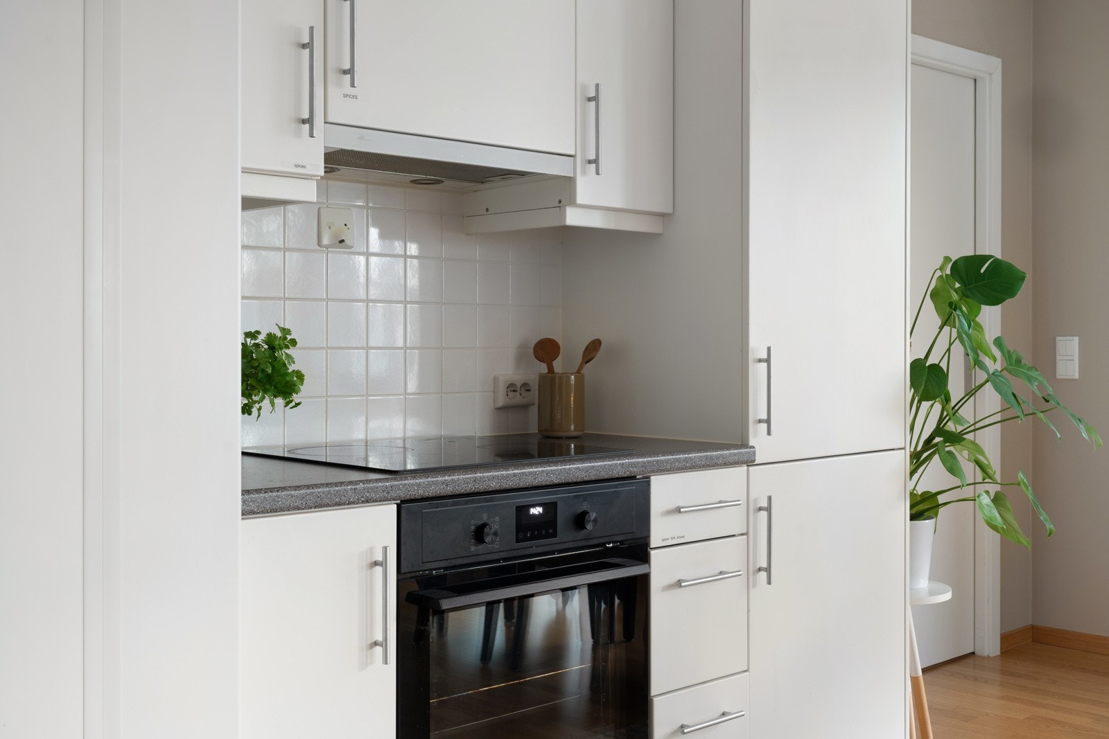 Integrerte hvitevarer og fliser som backsplash på vegg under skap.