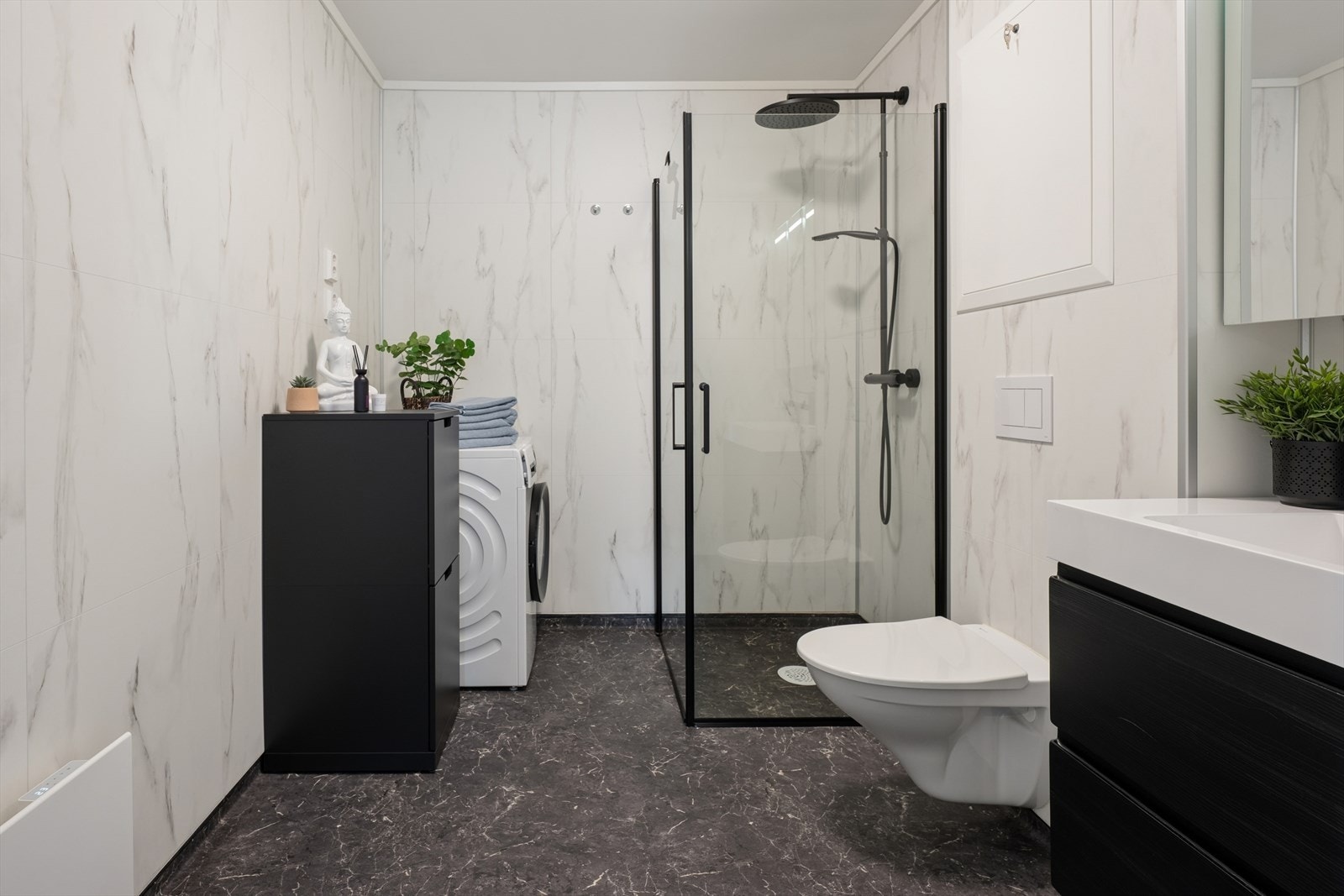 Badet har moderne baderomsplater i marmorlook, kombinert med gulvbelegg og malte glatte flater i himling. Galleribilde