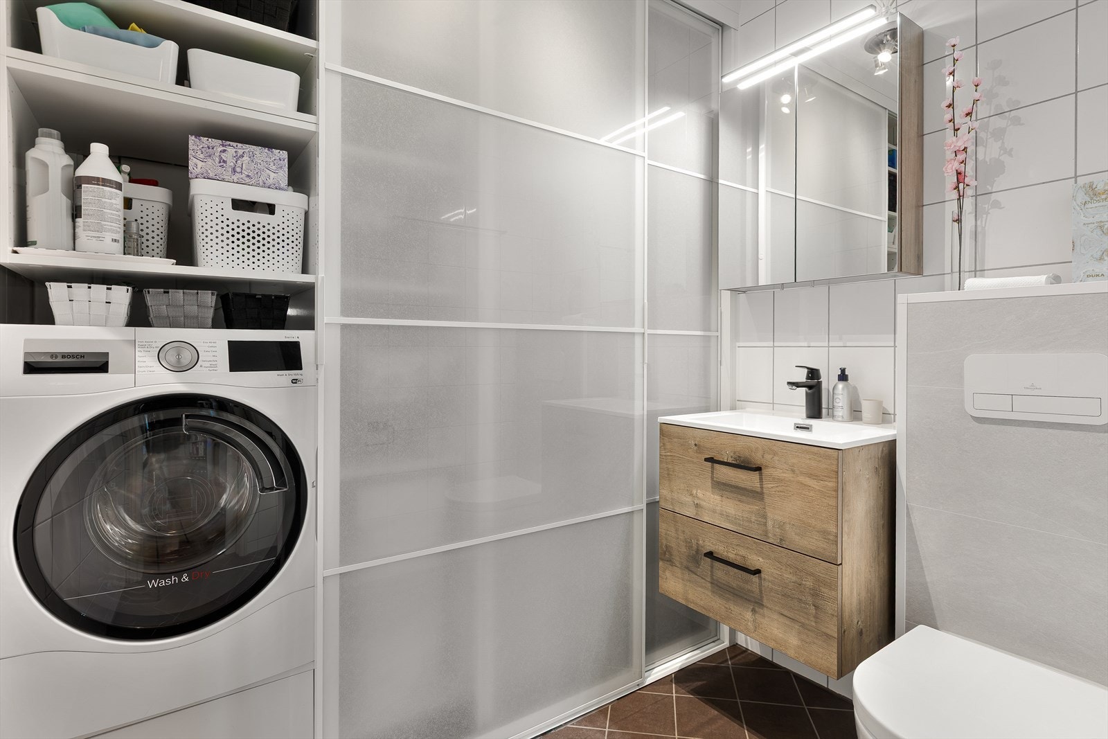 Vaskerommet har flislagte overflater og elektriske varmekabler, samt en svært smart plass til vaskemaskin. Galleribilde