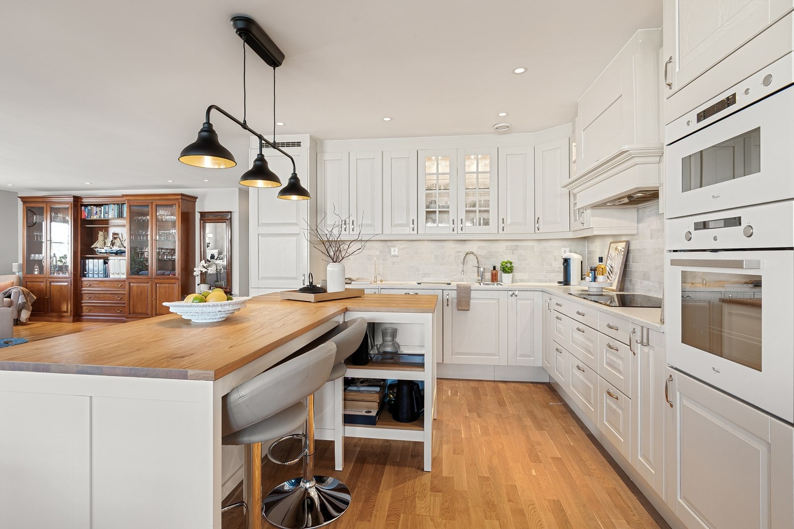 Detaljer som glassfronter og hvite, tidløse fargevalg, gir kjøkkenet et innbydende preg. Galleribilde