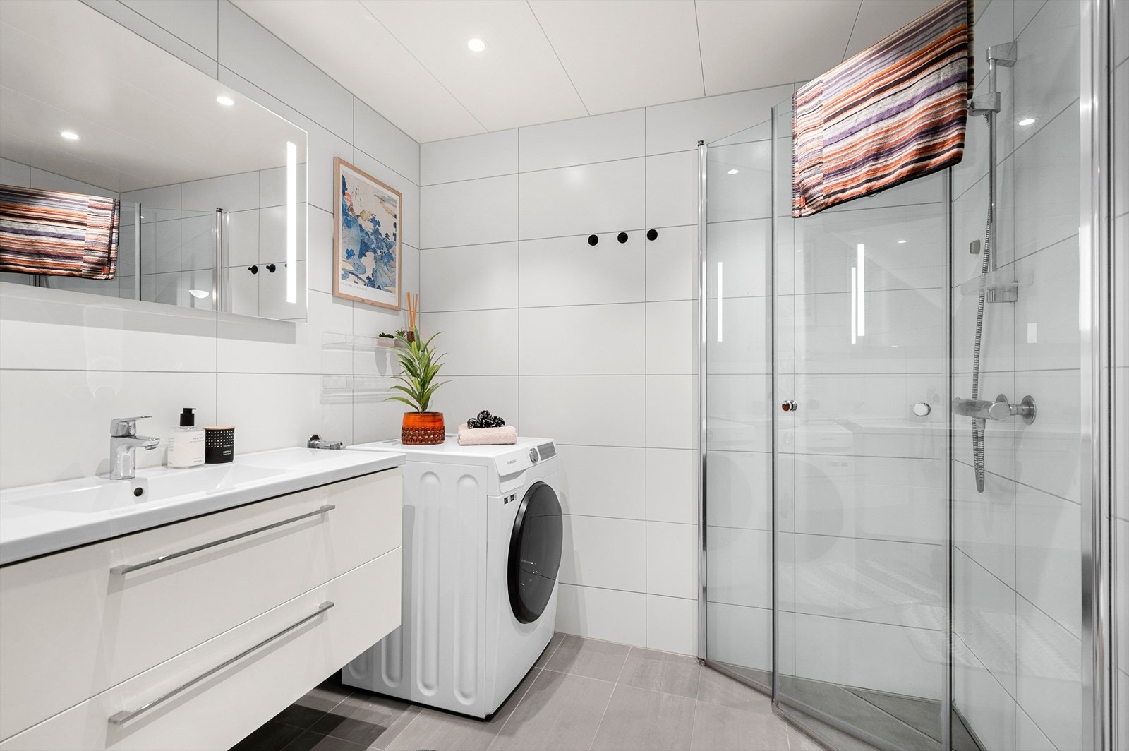 Pent flislagt baderom på 4,5 kvm. Her får du flott servant med underskap, dusjhjørne, vegghengt WC og opplegg for vaskemaskin Galleribilde