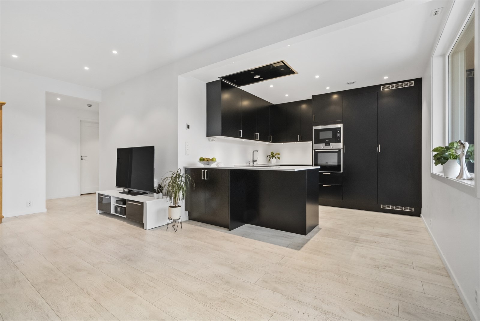 Kjøkkenet har HTH-innreiing med slette, mørke frontar og benkeplate i kvit laminat Galleribilde