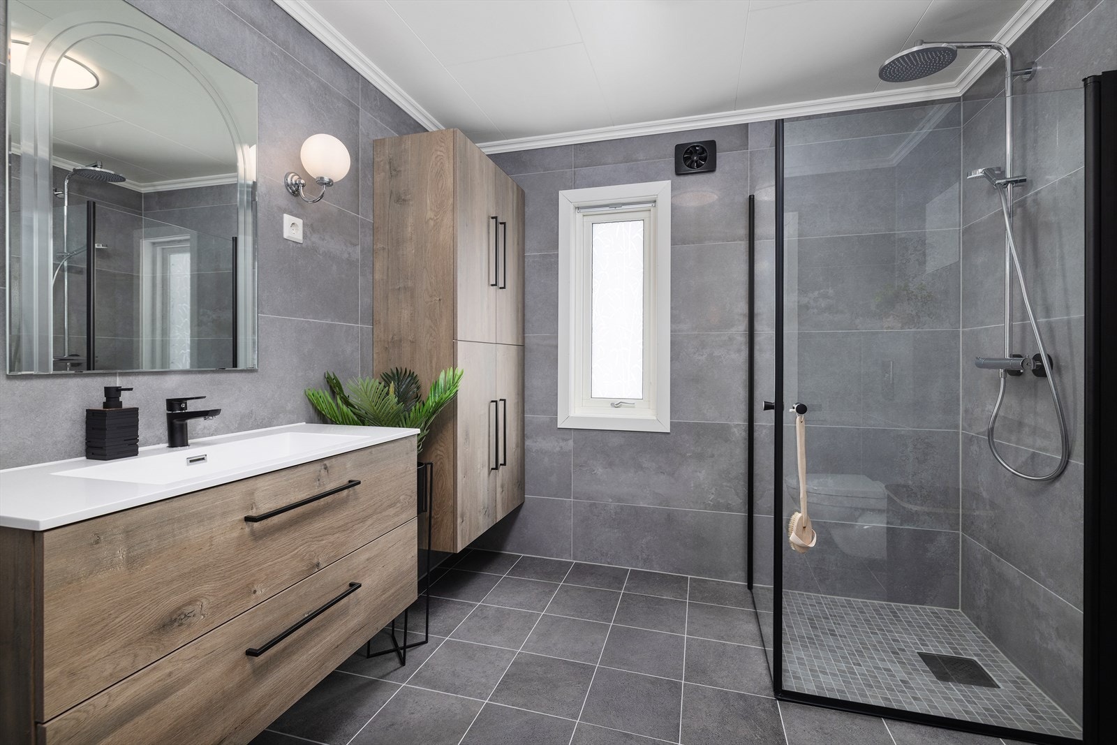 Badet har flislagt gulv med varmekabler, vegghengt toalett og et romslig dusjhjørne. Galleribilde