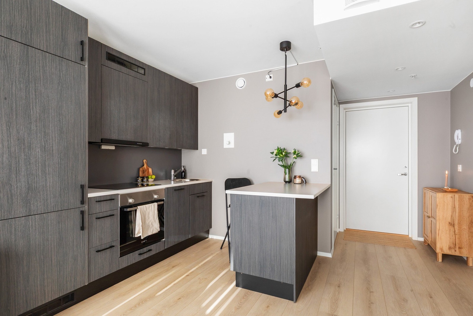 Mørkt lekkert kjøkken med lys benkeplate i kontrast, og med tilhørende kjøkkenøy hvor du får sitteplasser og ekstra oppbevaring Galleribilde