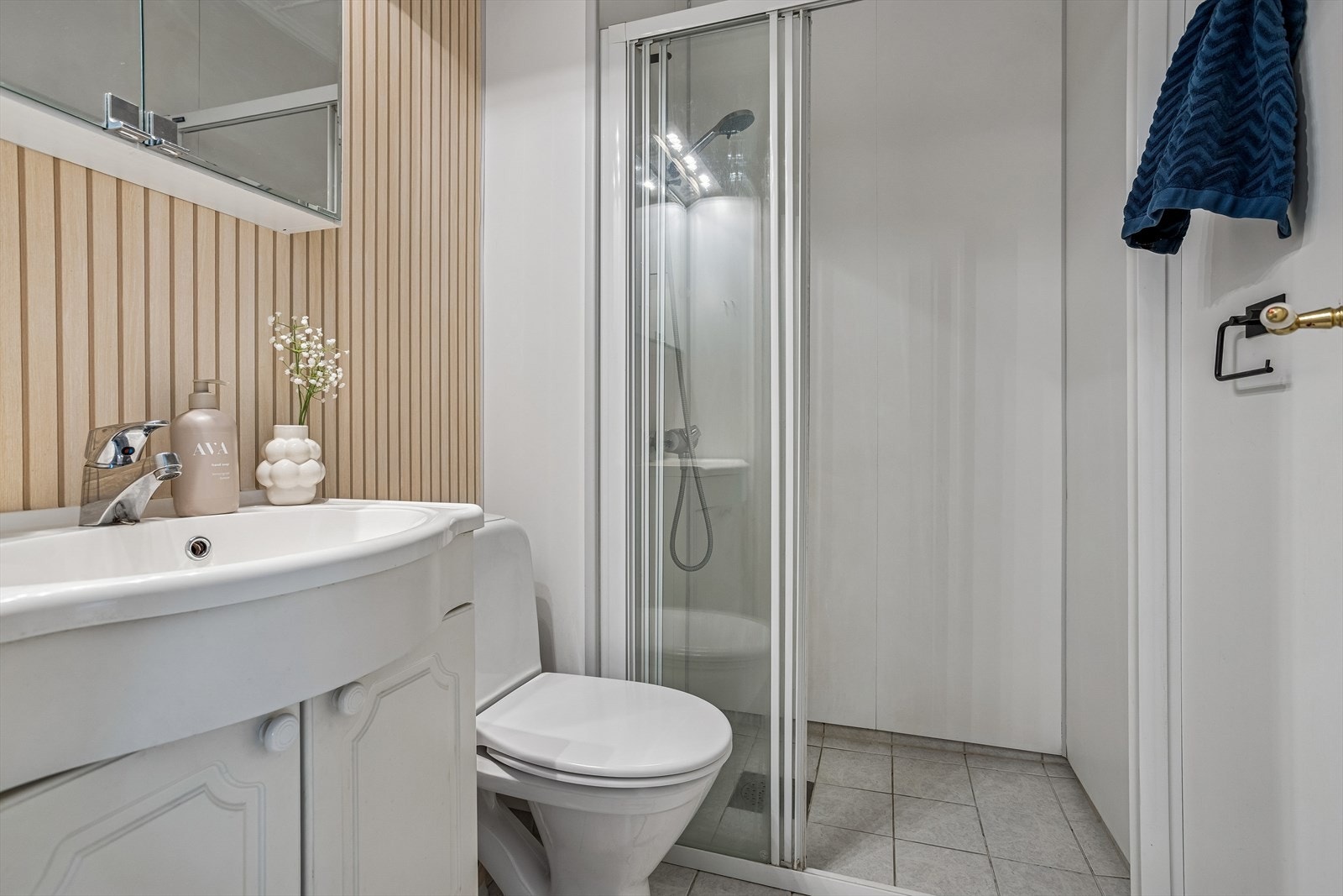 Badet har flislagt gulv med varme, vegger med baderomsplater og en praktisk dusjvegg i glass. Galleribilde