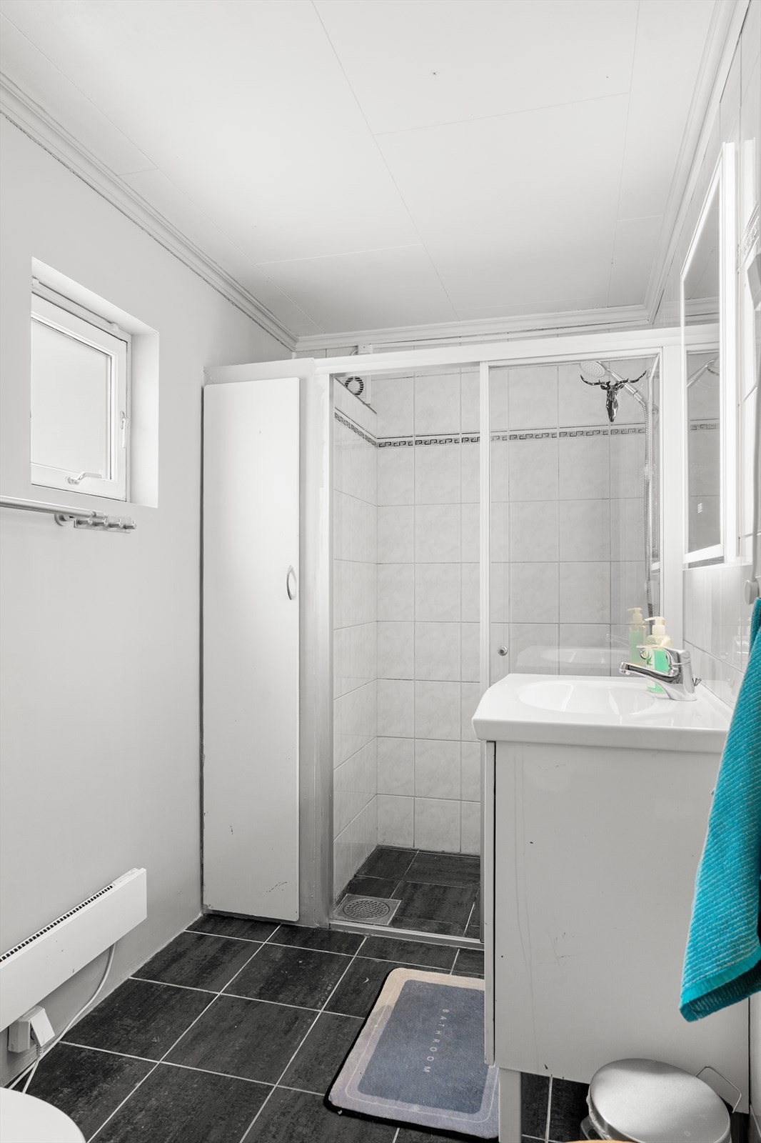 Lyst bad i 1. etasje med fliser på vegger og gulv - veggen mot nord er behandlet med mikrosement Galleribilde