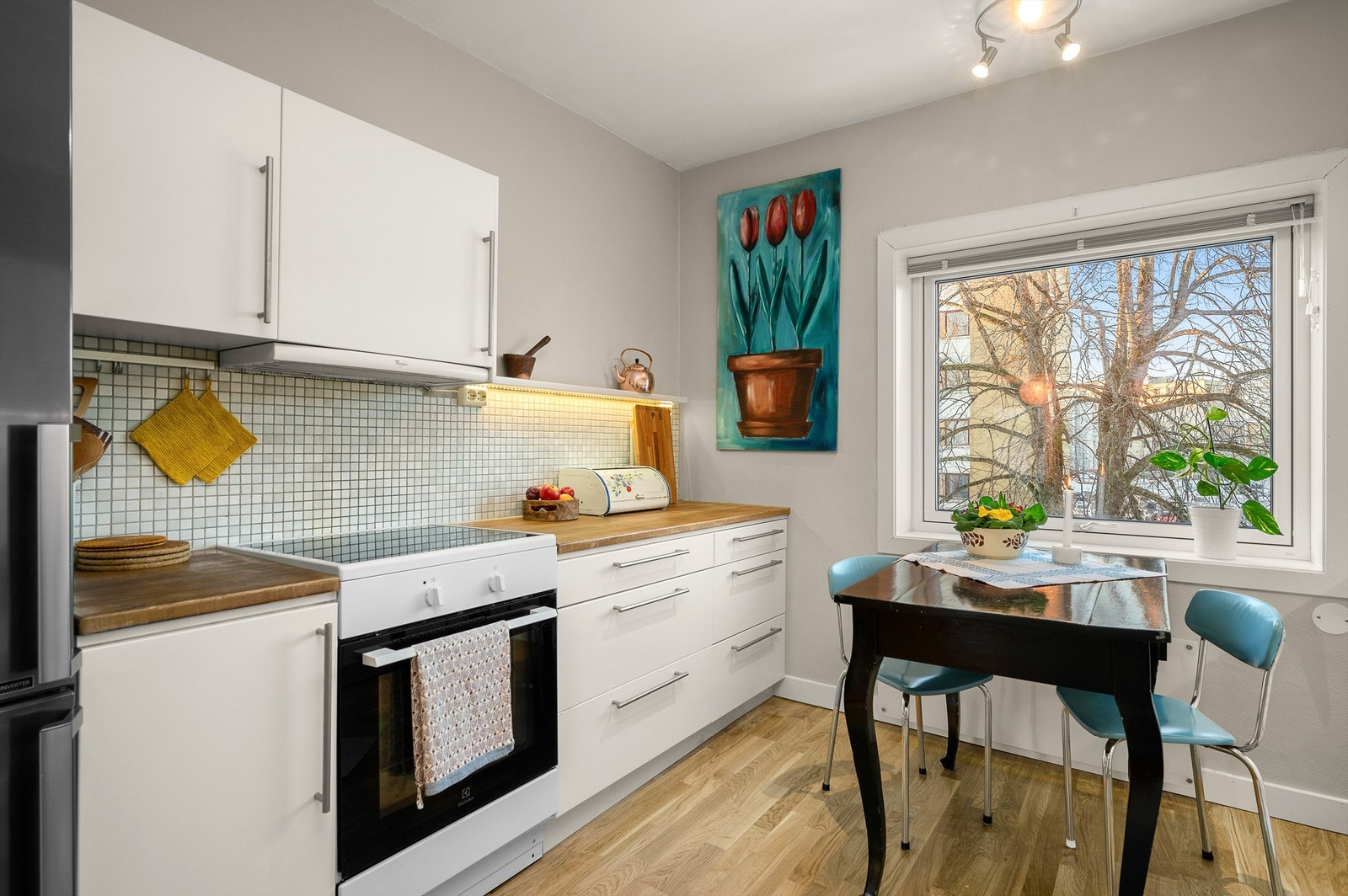 Kjøkkenet ligger naturlig tilbaketrukket fra stuen og er innredet med lyse slette flater og benkeplate av tre og rustfritt stål. Galleribilde