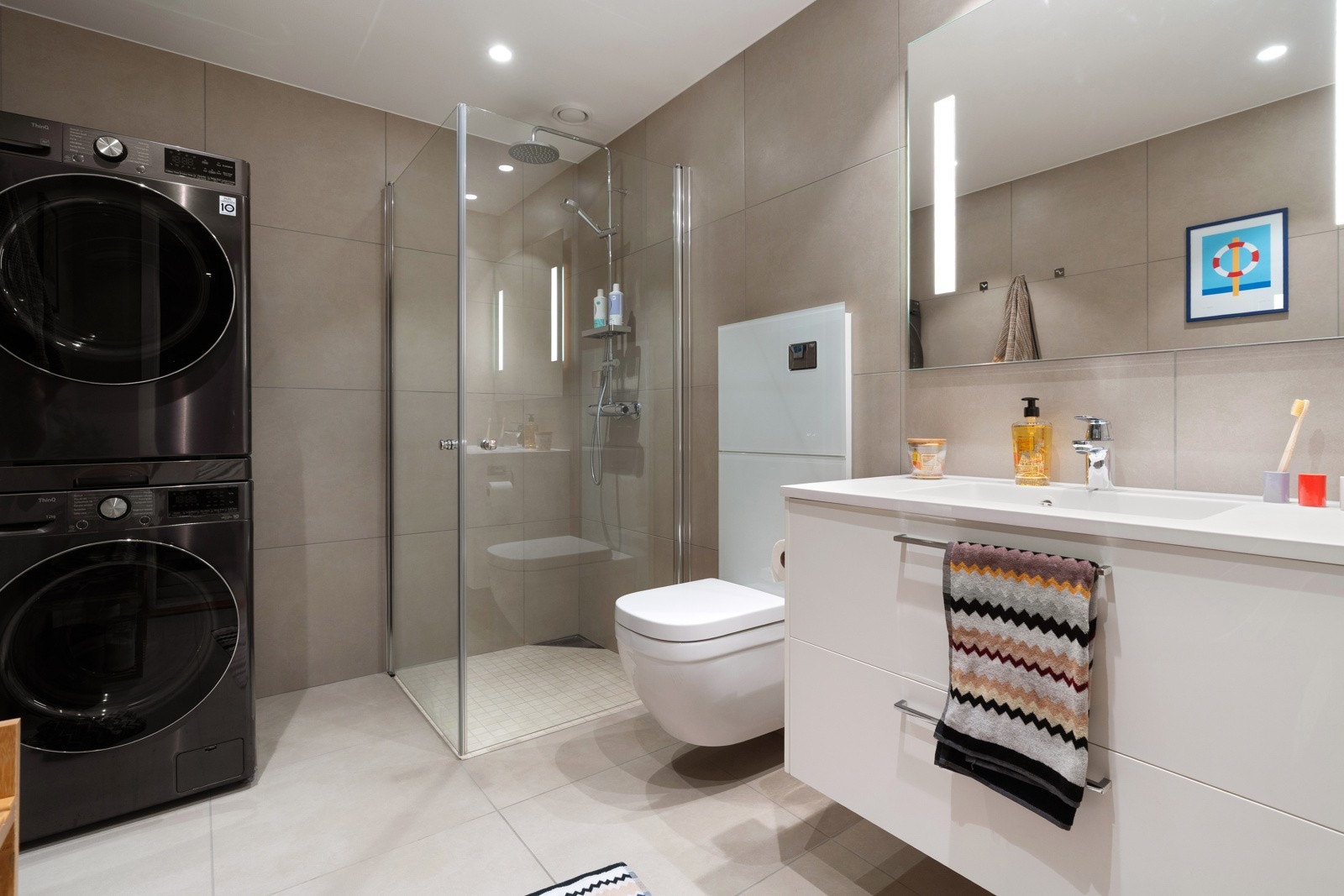 Baderomsinnredning med praktiske skuffer og speil med belysning.