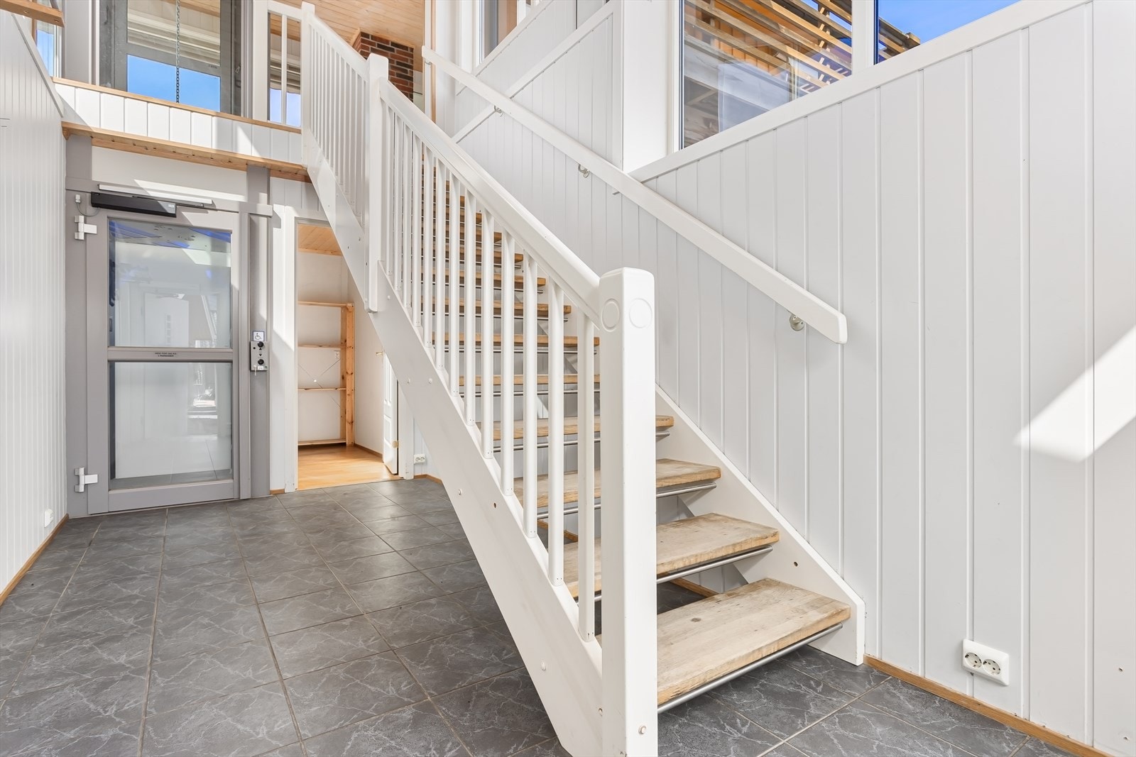 Velkommen inn! Med utvendig adkomst og adkomst fra garasje er det en flott hall med både trapp og heis opp til 1. etasje. Galleribilde