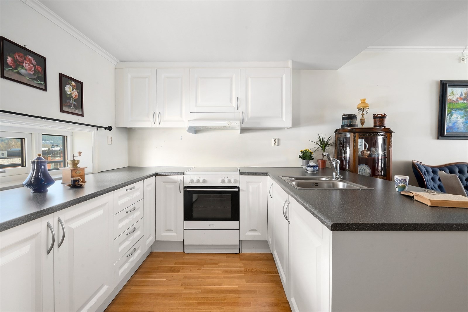 Pent kjøkken med hvite profilerte fronter og benkeplate av laminat. Galleribilde