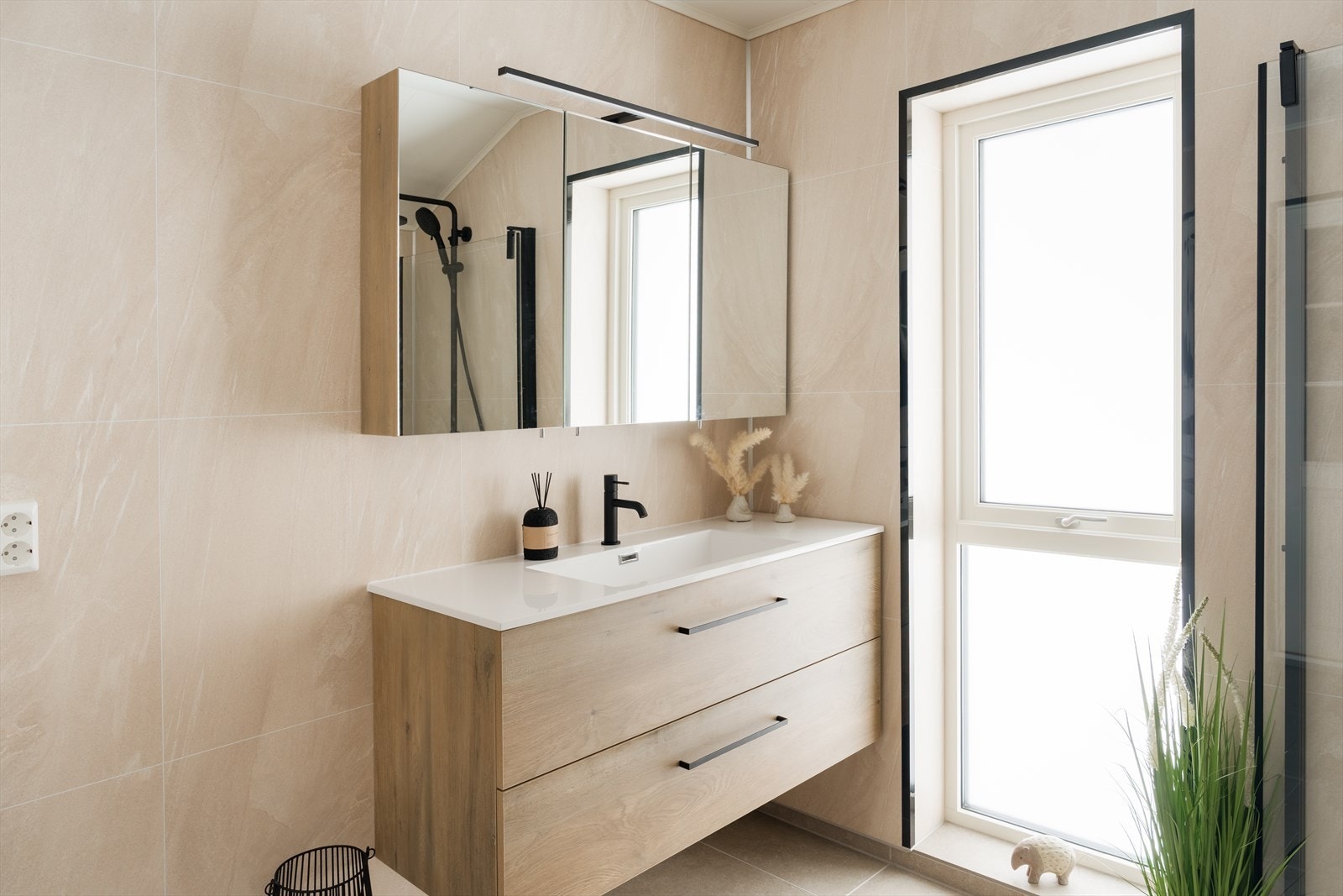 Badet er utstyrt med baderomsinnredning med nedfelt servant, toalett, dusjvegger og opplegg for vaskemaskin Galleribilde