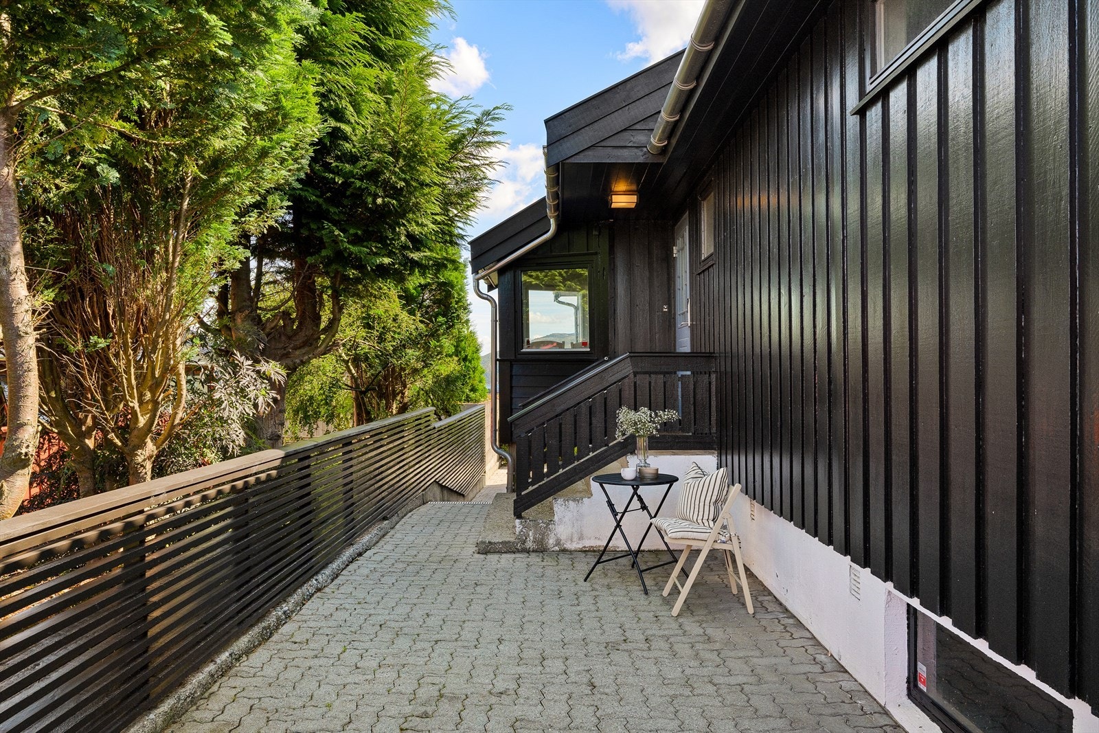 Innbydende og skjermet inngangsparti med belegningsstein og hyggelig sitteplass. Galleribilde