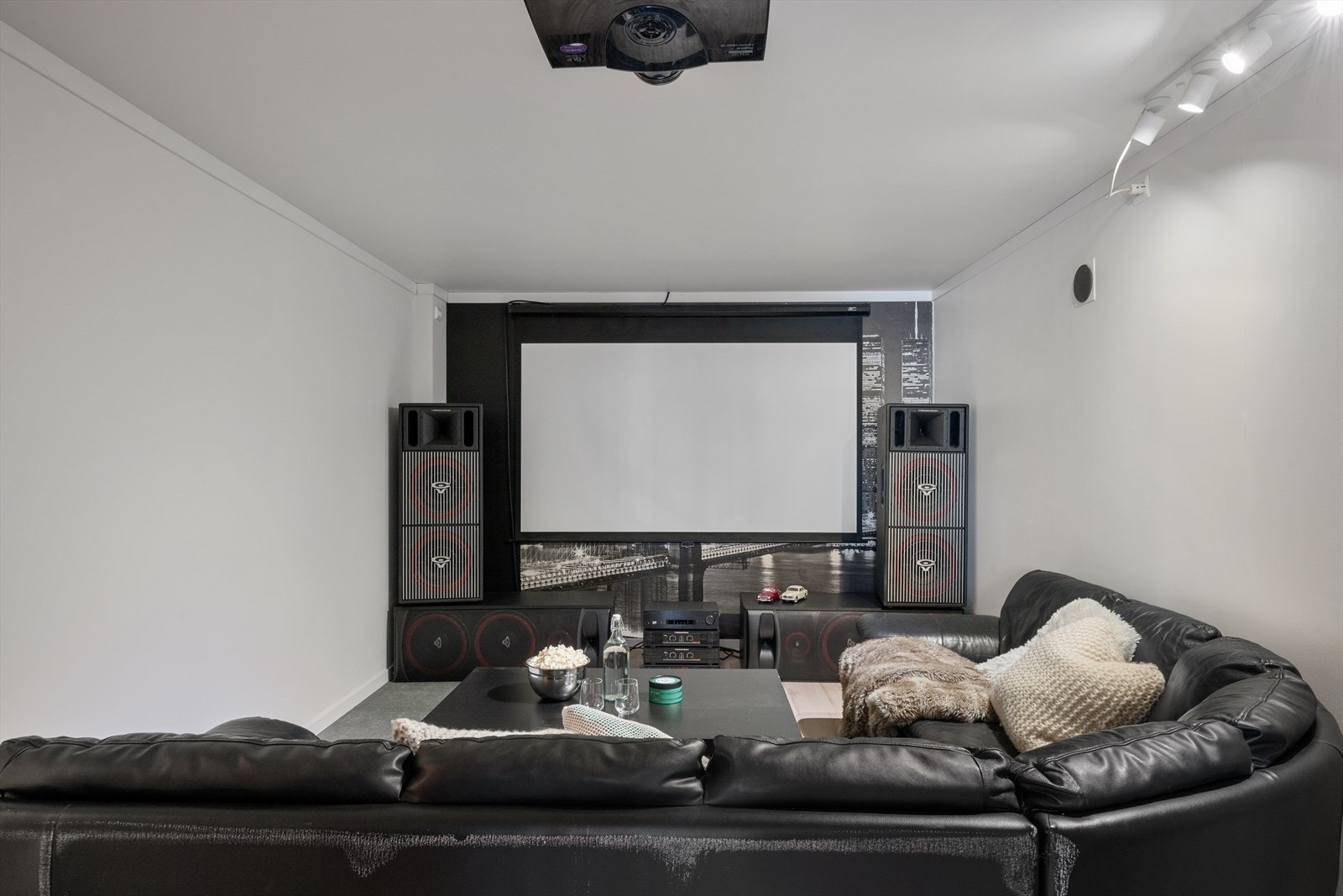 En kjellerstue forvandlet til en imponerende hjemmekino, komplett med kraftig lydanlegg og høykvalitets projektor - perfekt for en oppslukende filmopplevelse. Galleribilde