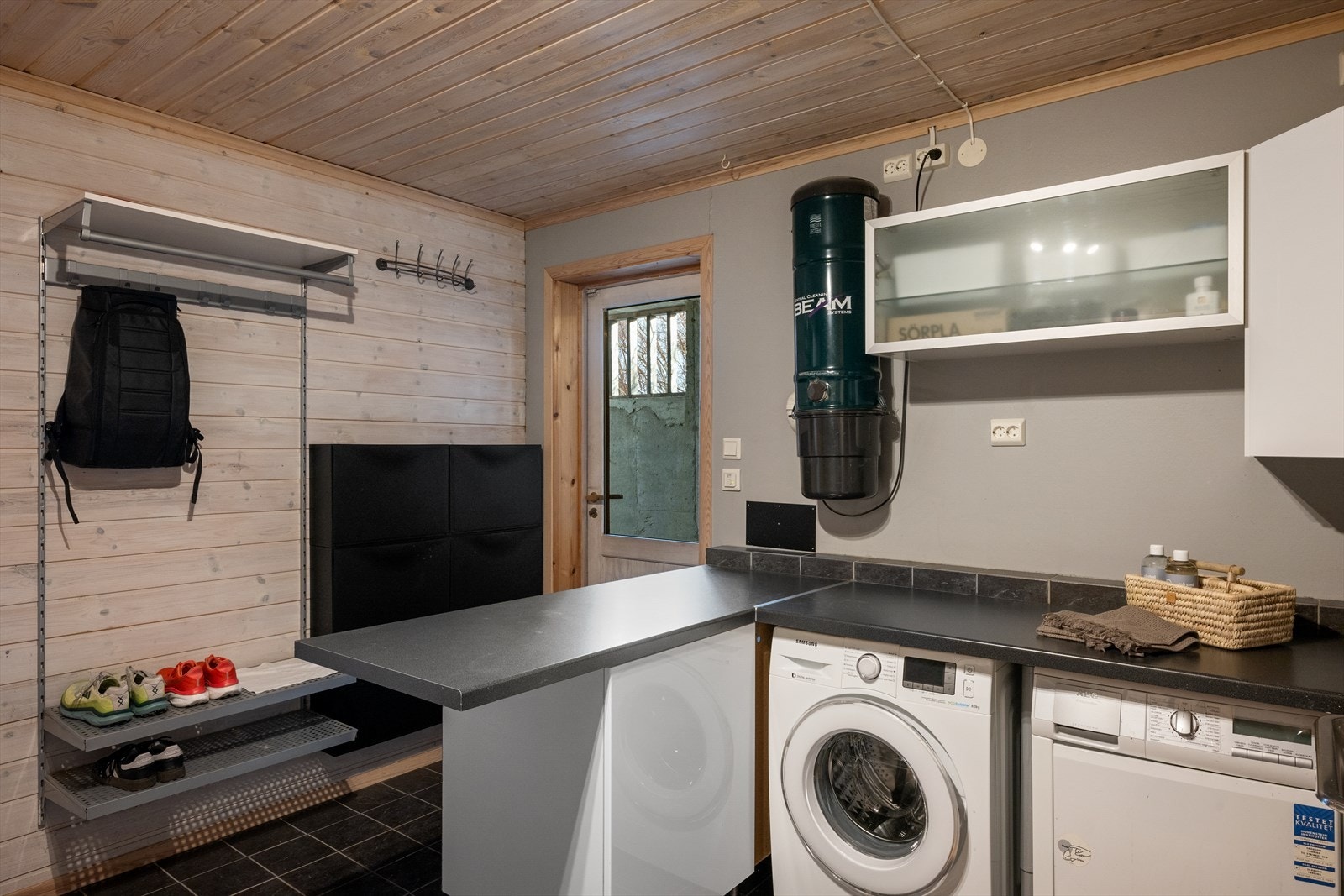 Vaskerommet i kjelleren er praktisk og funksjonelt med flislagt gulv og lokalt fall ved sluk. I tillegg har rommet både opplegg for vaskemaskin og utslagsvask, noe som gjør klesvasken enkel og effektiv. Galleribilde