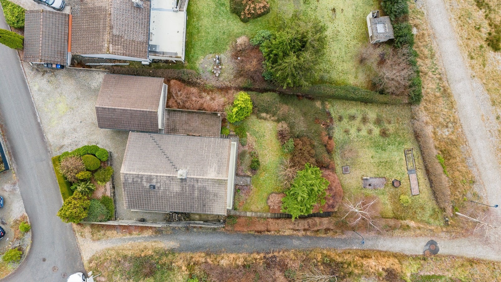 Tomten er opparbeidet med beplantning, plen, gårdsplass og platting Galleribilde