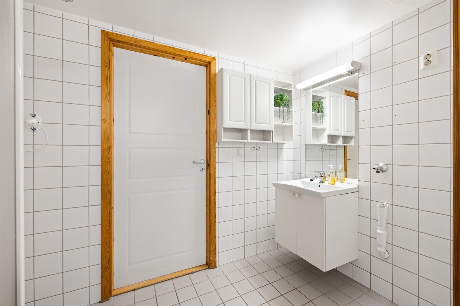 Flislagt baderom med vegghengt servantinnredning og speil med overlys. Galleribilde