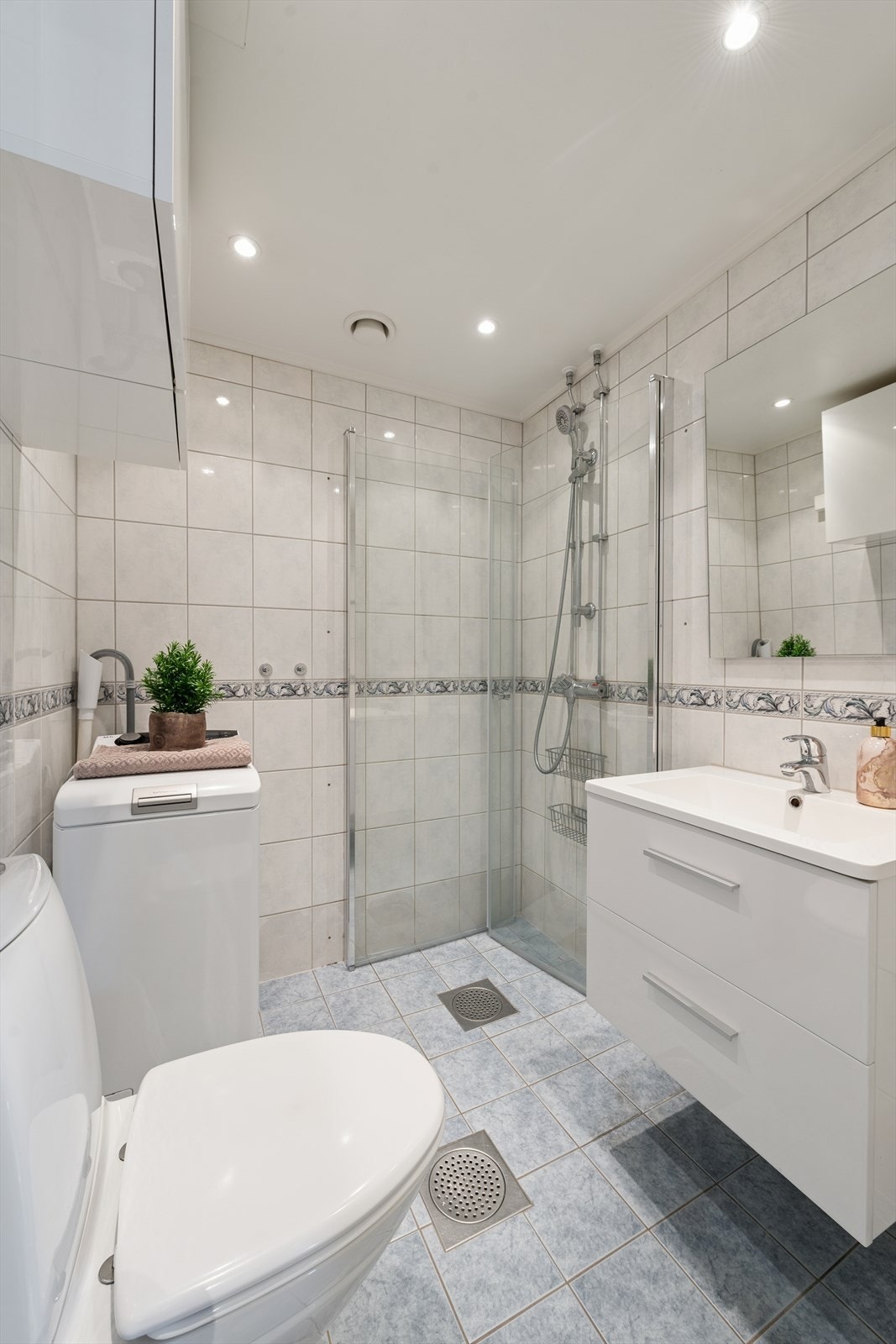 Badet er innredet med servantinnredning, gulvmontert toalett og dusjhjørne med innfellbare glassdører. Det er også opplegg for vaskemaskin. Galleribilde