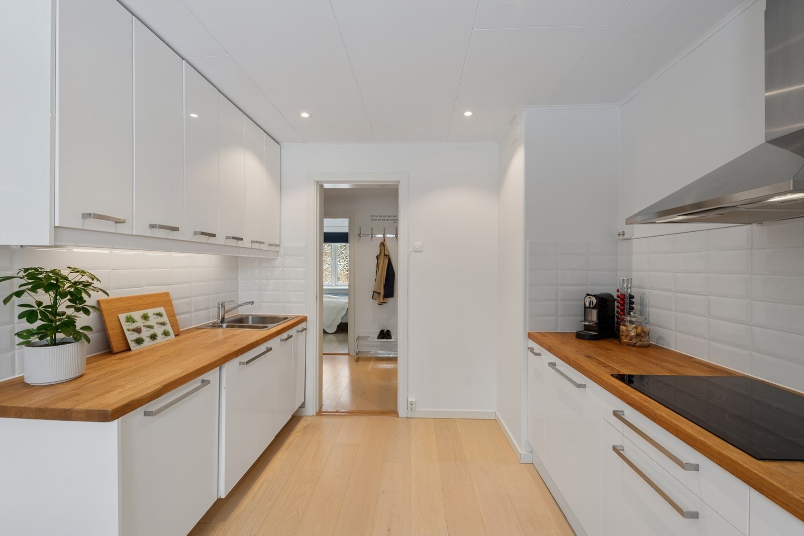 Kjøkkenet har en lekker og tidløs innredning fra 2015 med hvite, glatte fronter og heltre benkeplate med nedfelt kjøkkenkum. Galleribilde