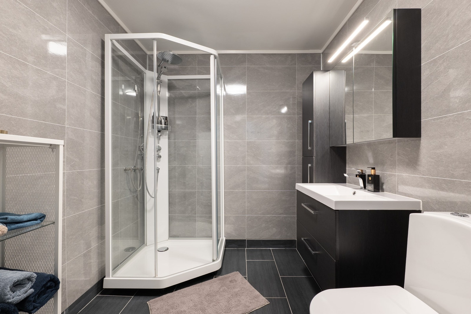 Baderomsinnredning med dusjkabinett, nedfelt servant og opplegg for vaskemaskin. Galleribilde