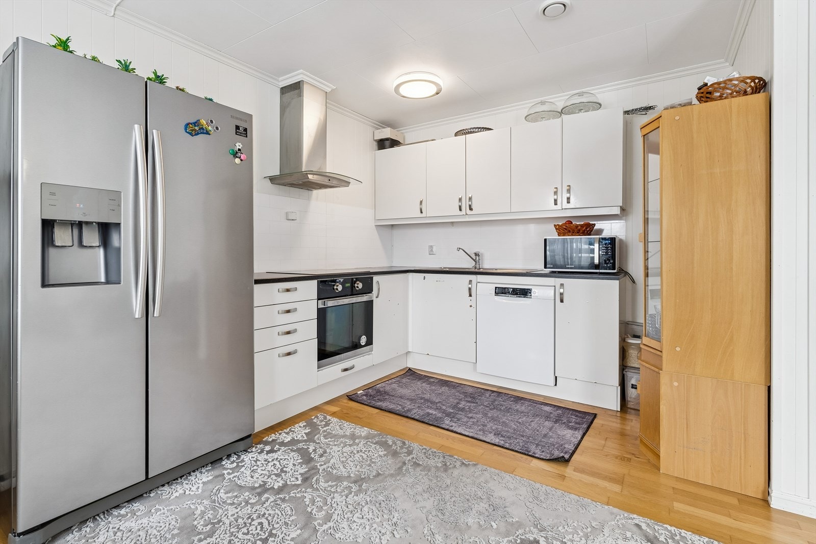 Kjøkkeninnredningen har glatte fronter og integrerte hvitevarer som platetopp og stekeovn. Galleribilde