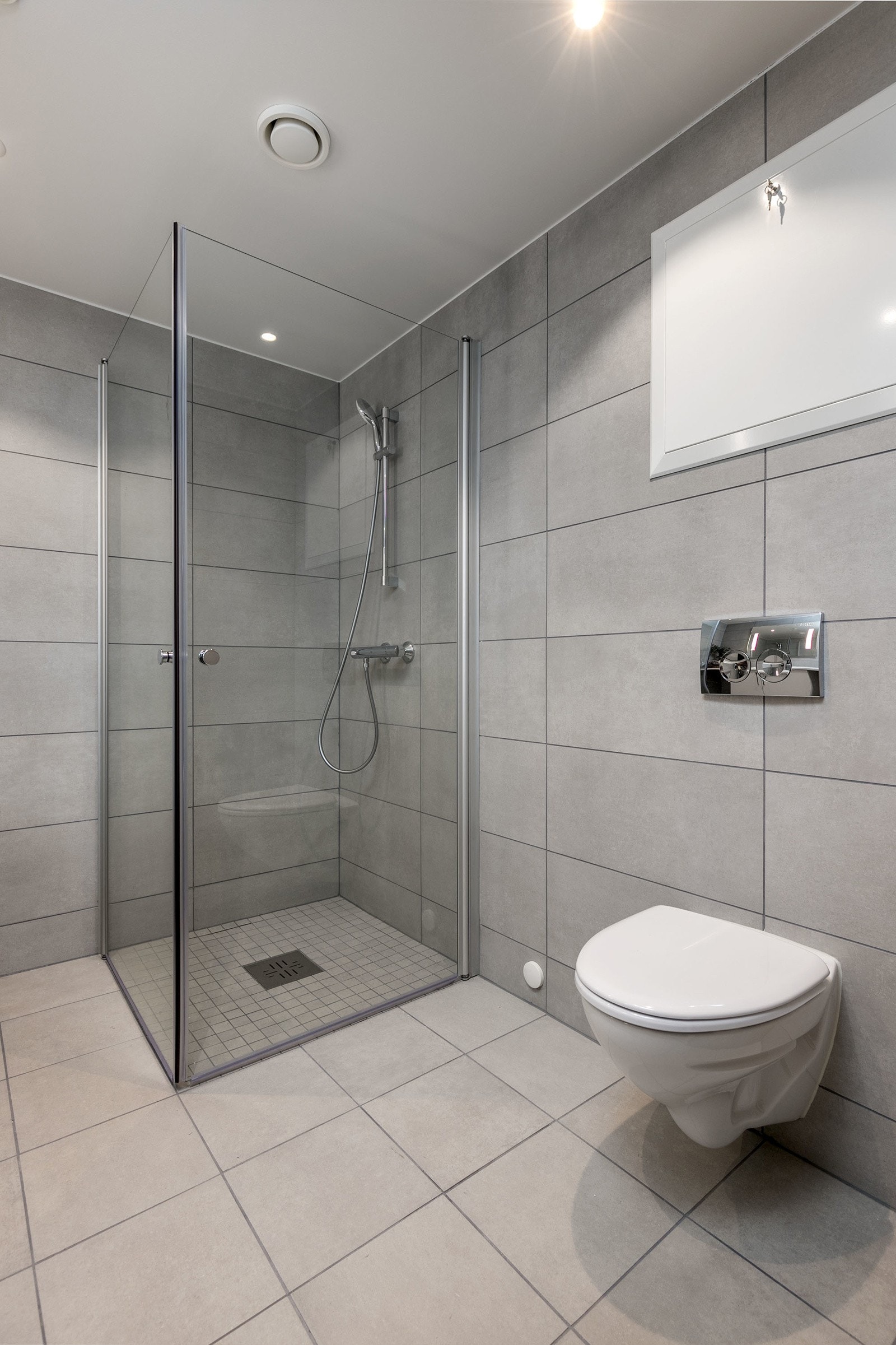 Badet har vegghengt toalett med innbygget sisterne, servant med skapinnredning samt speil med belysning. Bilde fra M507 Galleribilde