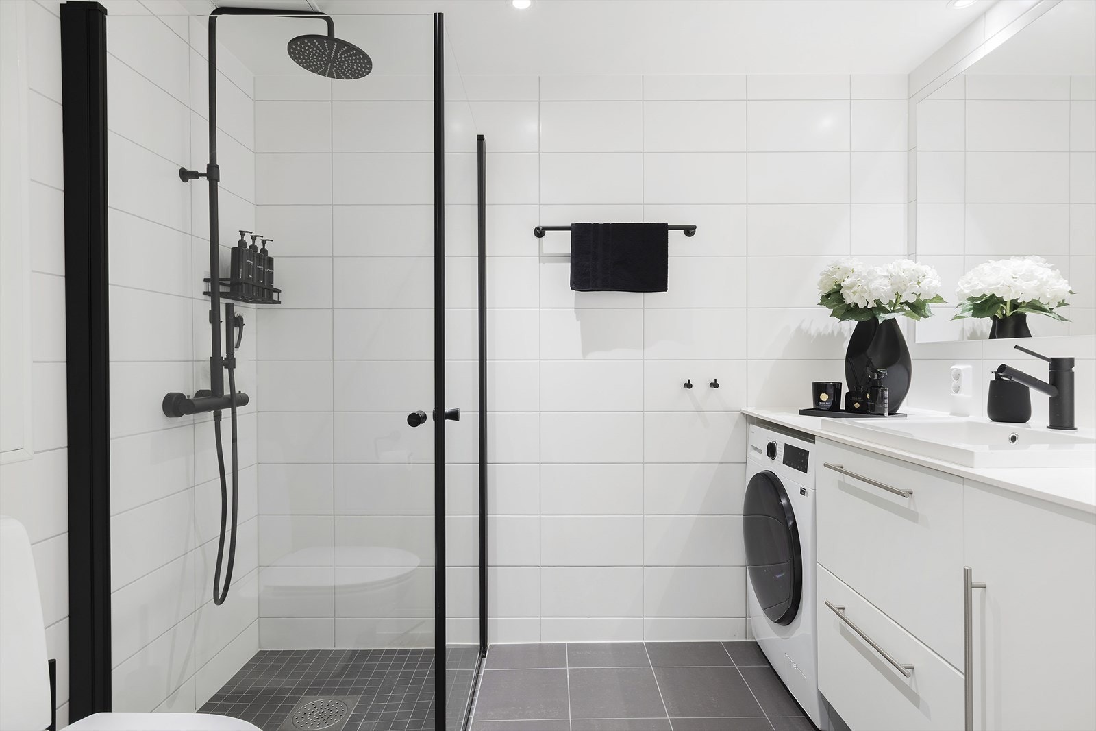 Delikat, flislagt bad med dusjhjørne og vegghengt toalett. Galleribilde