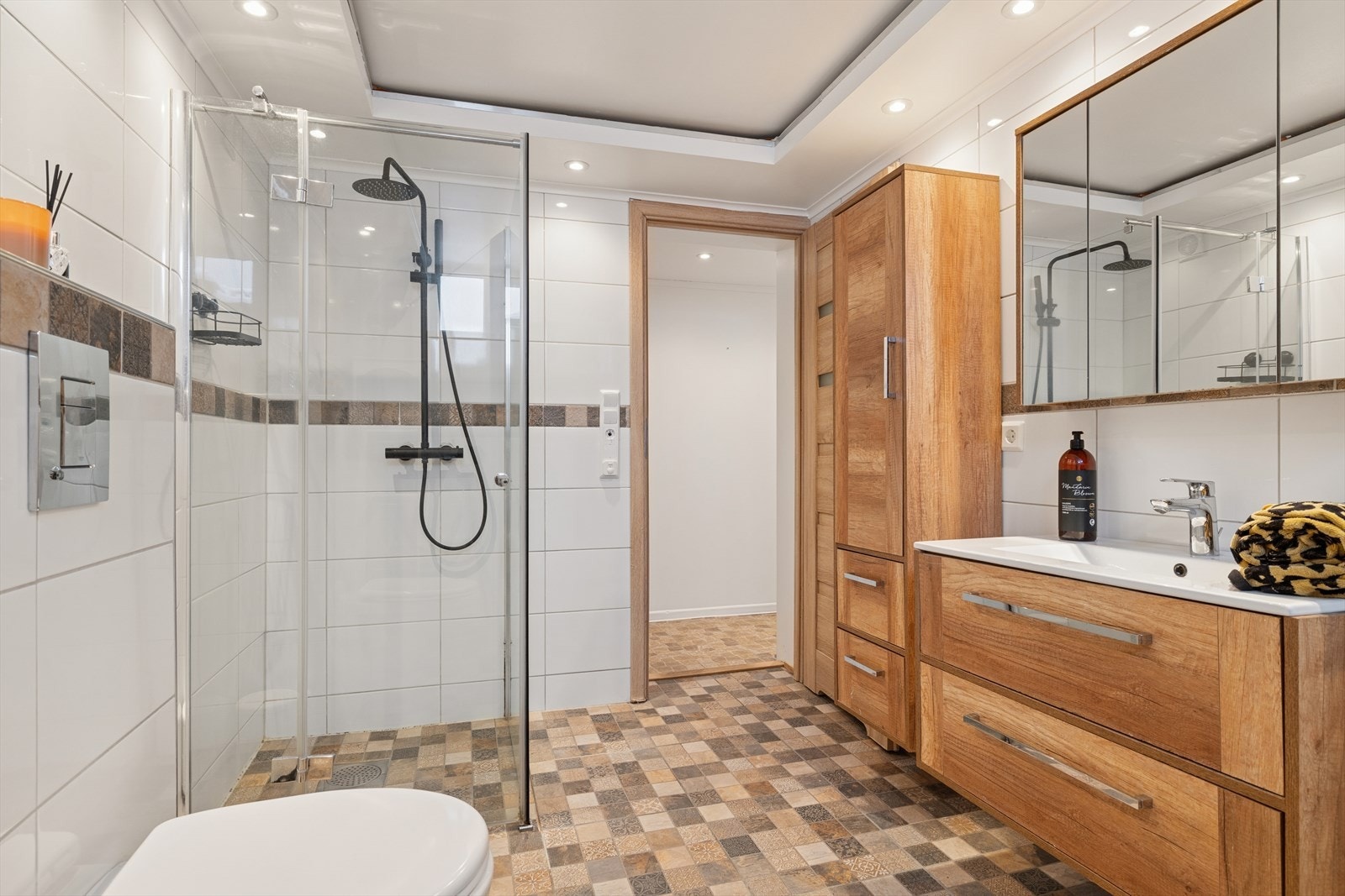 Badet er innredet med vegghengt toalett, dusjhjørne, servantinnredning og et praktisk høyskap, samt speilskap over servanten. Galleribilde