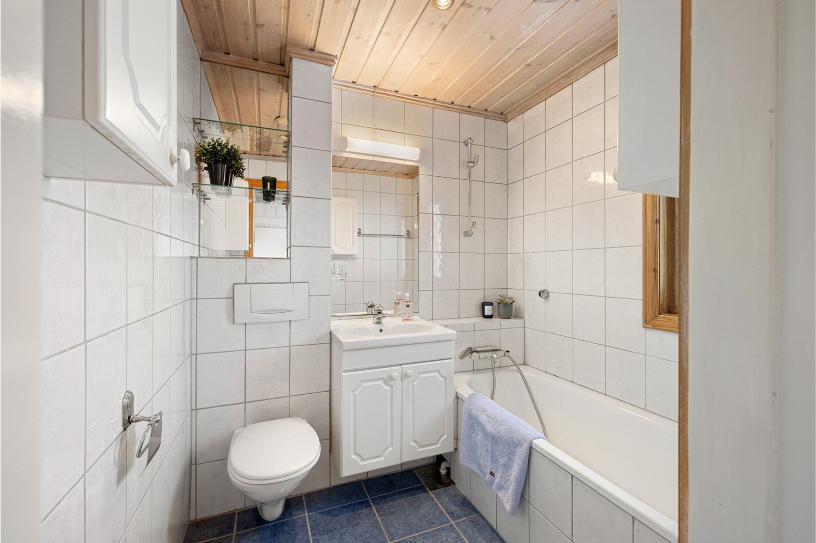 Flislagt bad med gulvvarme og vindu som gir naturlig lys og god ventilasjon. Galleribilde