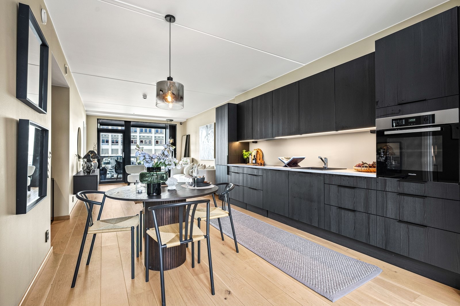 Kjøkkenet er innredet med elegant og moderne kjøkkenløsning fra HTH med glatte fronter i en mørk, moderne fargepalett, samt benkeplate i slitesterk laminat. Galleribilde