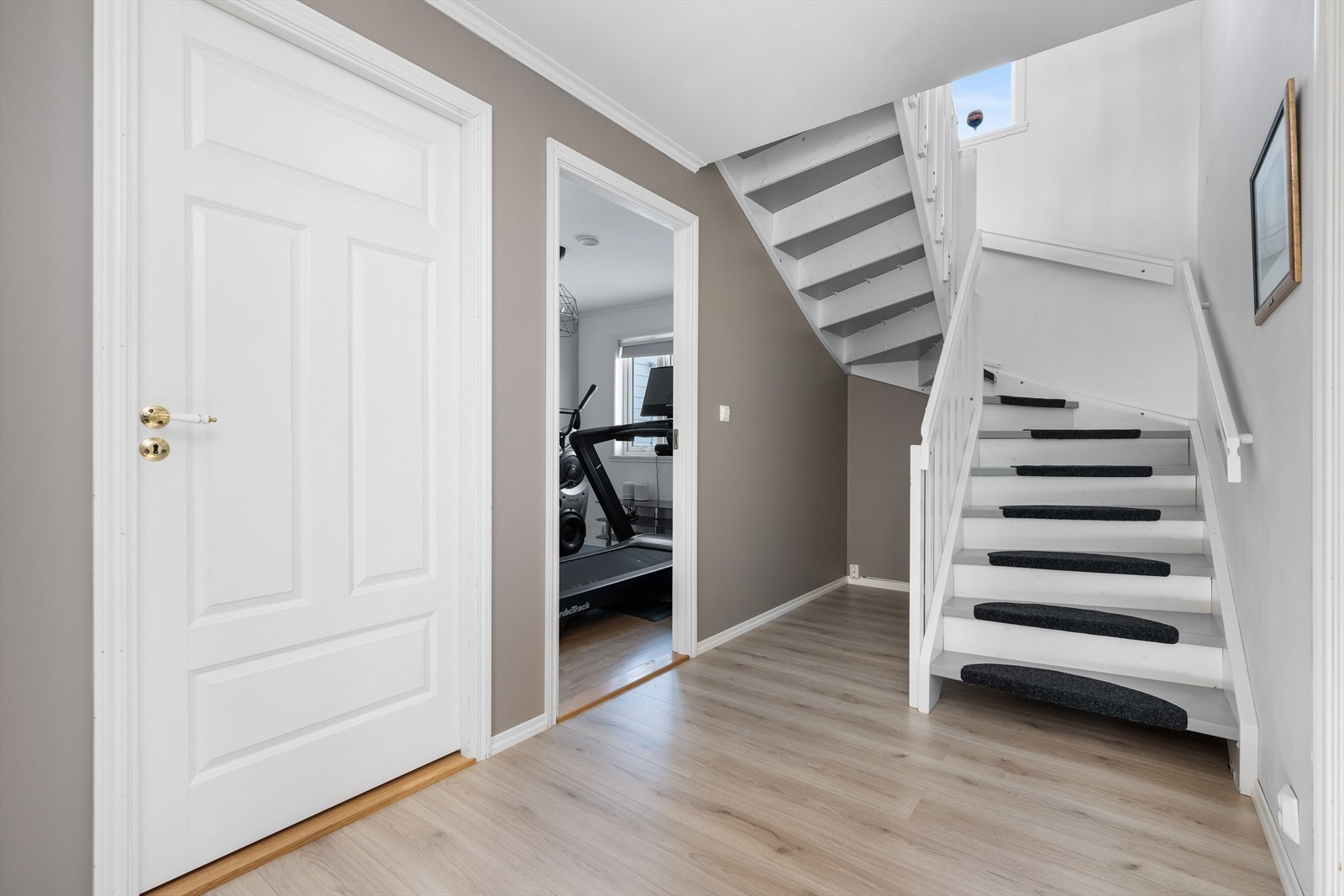 Romslig hall med trapp opp til andre etasje. Moderne fargevalg på vegger. Galleribilde