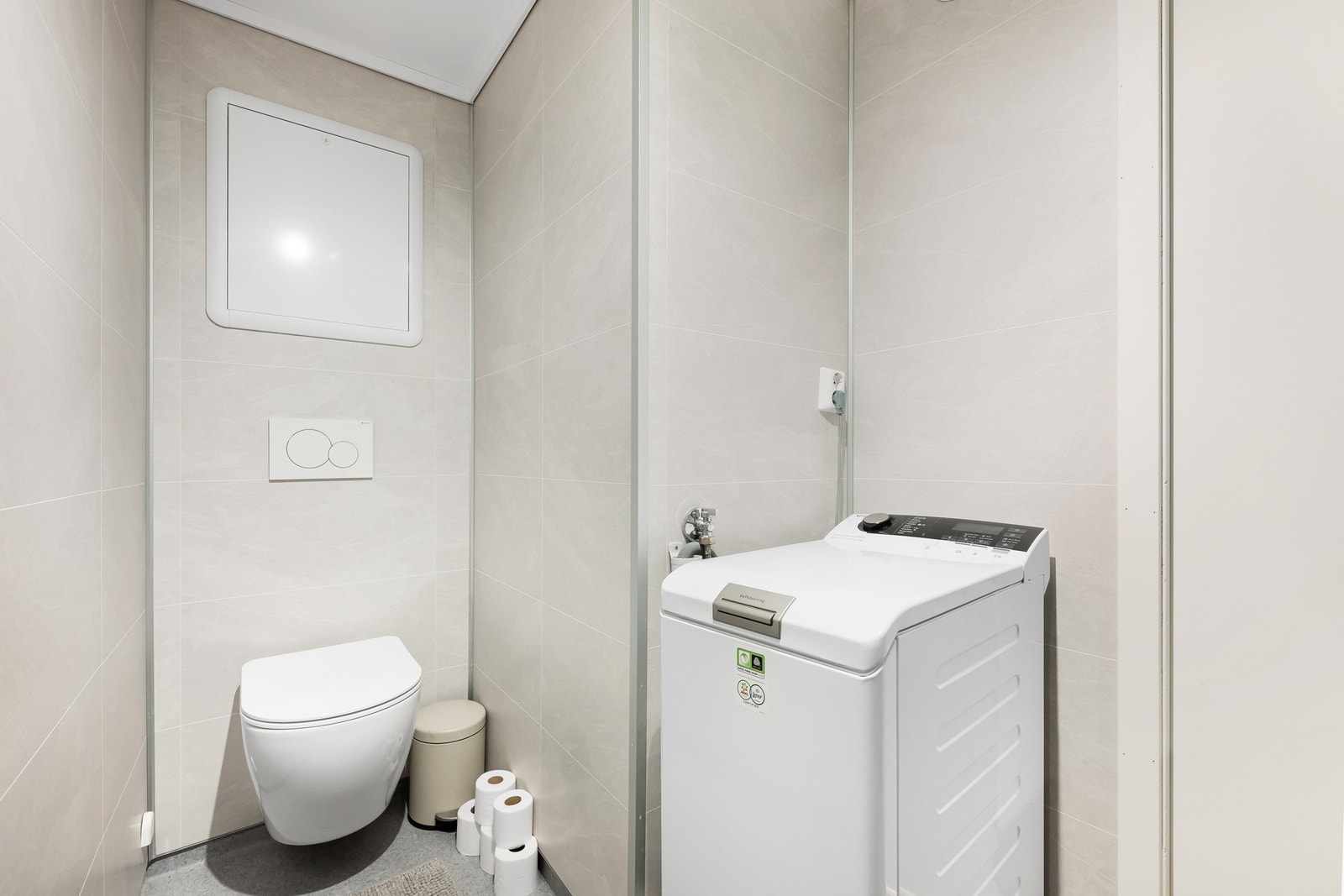 Dette inneholder vegghengt toalett, helstøpt servant, skuffer under servant med slette fronter, dusjdører i klart glass, og har opplegg for vaskemaskin. Galleribilde