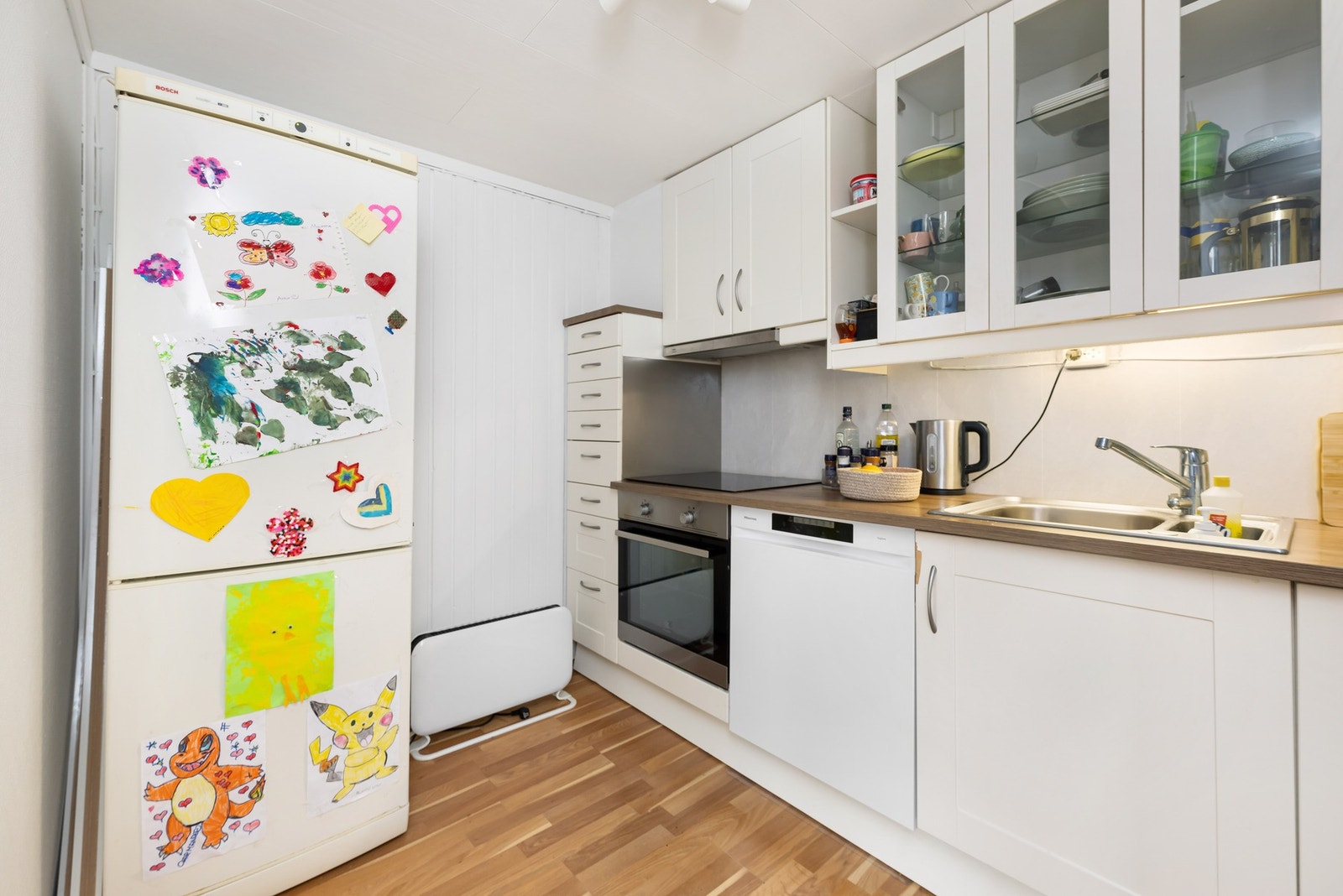 Rom innredet som kjøkken, med profilerte fronter, to overskap med glassfronter, og laminat benkeplate. Galleribilde